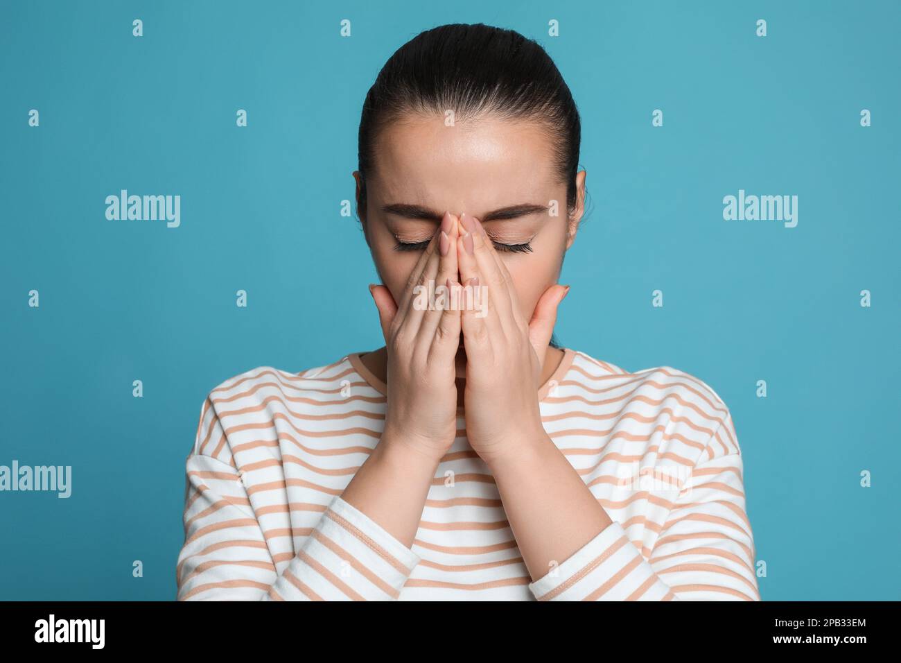 Giovane donna che soffre di mal di testa su sfondo azzurro Foto Stock