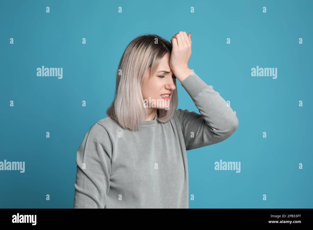 Donna che soffre di mal di testa su sfondo azzurro Foto Stock