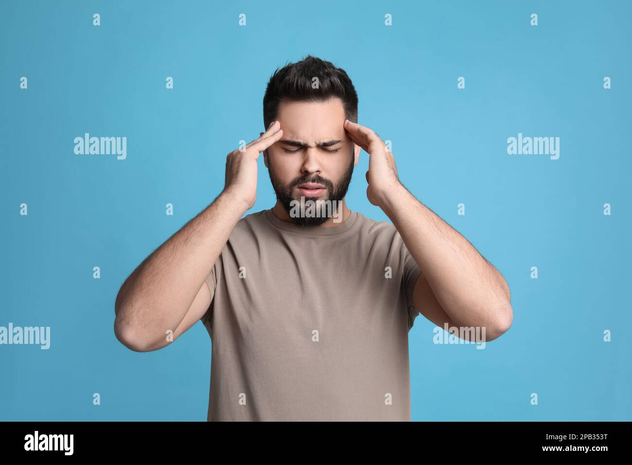 Giovane uomo che soffre di mal di testa su sfondo azzurro Foto Stock