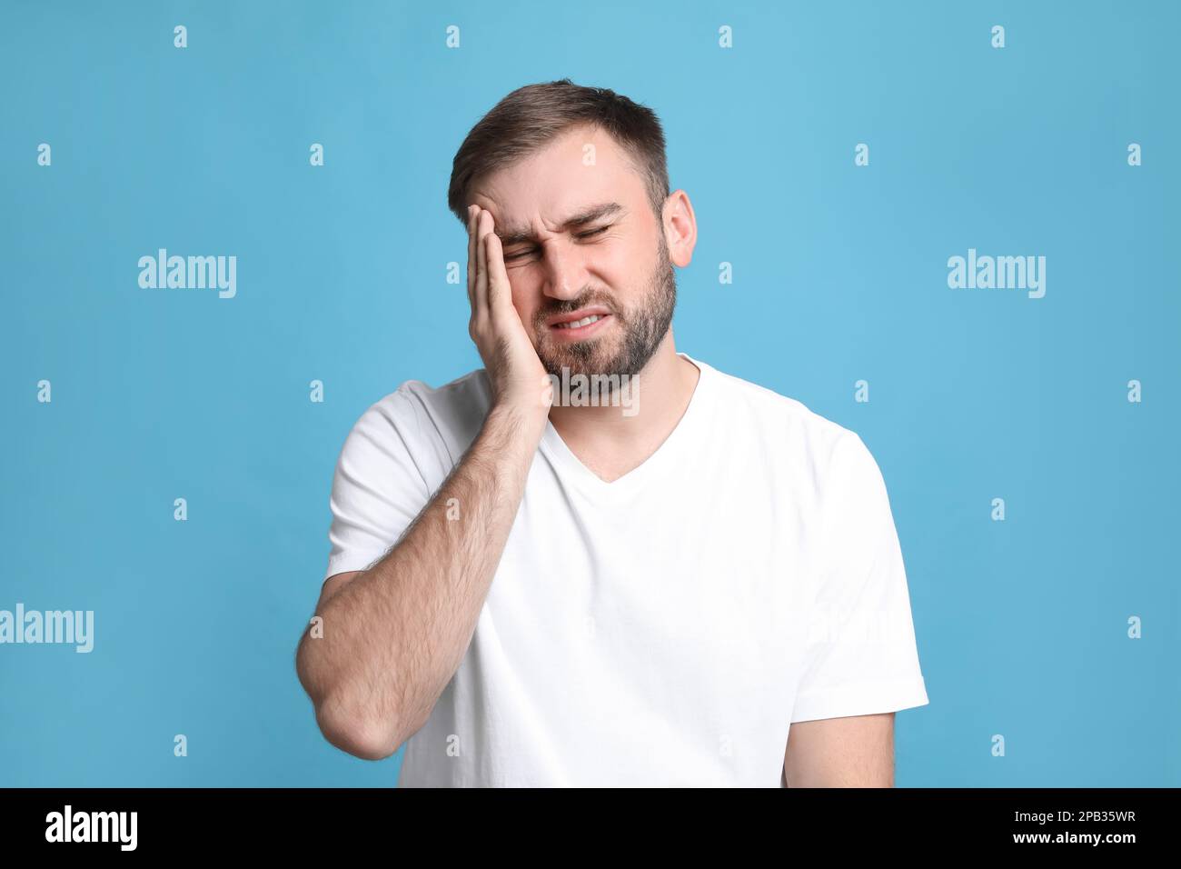 Giovane uomo che soffre di mal di testa su sfondo azzurro Foto Stock