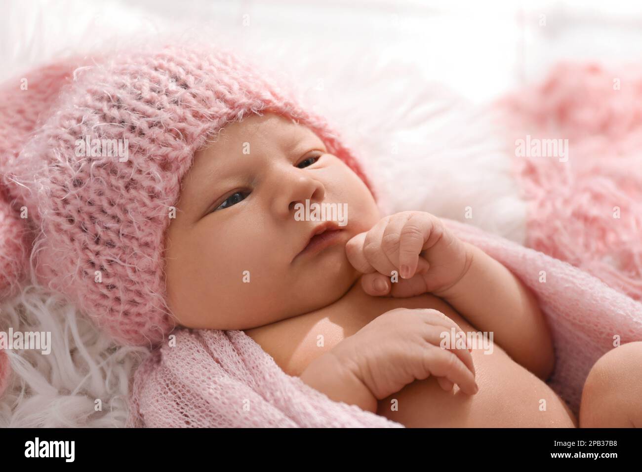 Cute neonato in cappello giacente su coperta fuzzy, primo piano Foto Stock