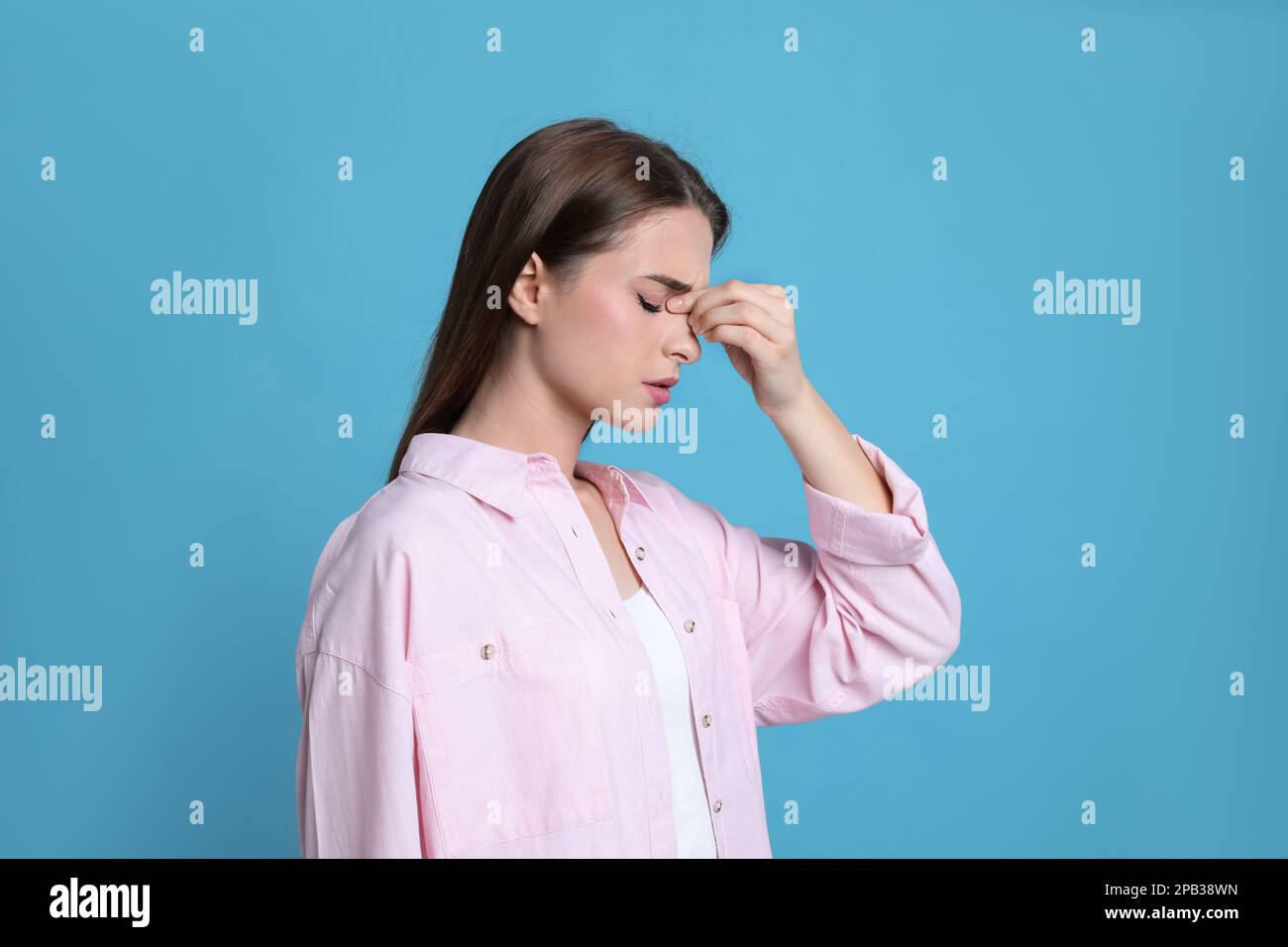 Giovane donna che soffre di mal di testa su sfondo azzurro Foto Stock