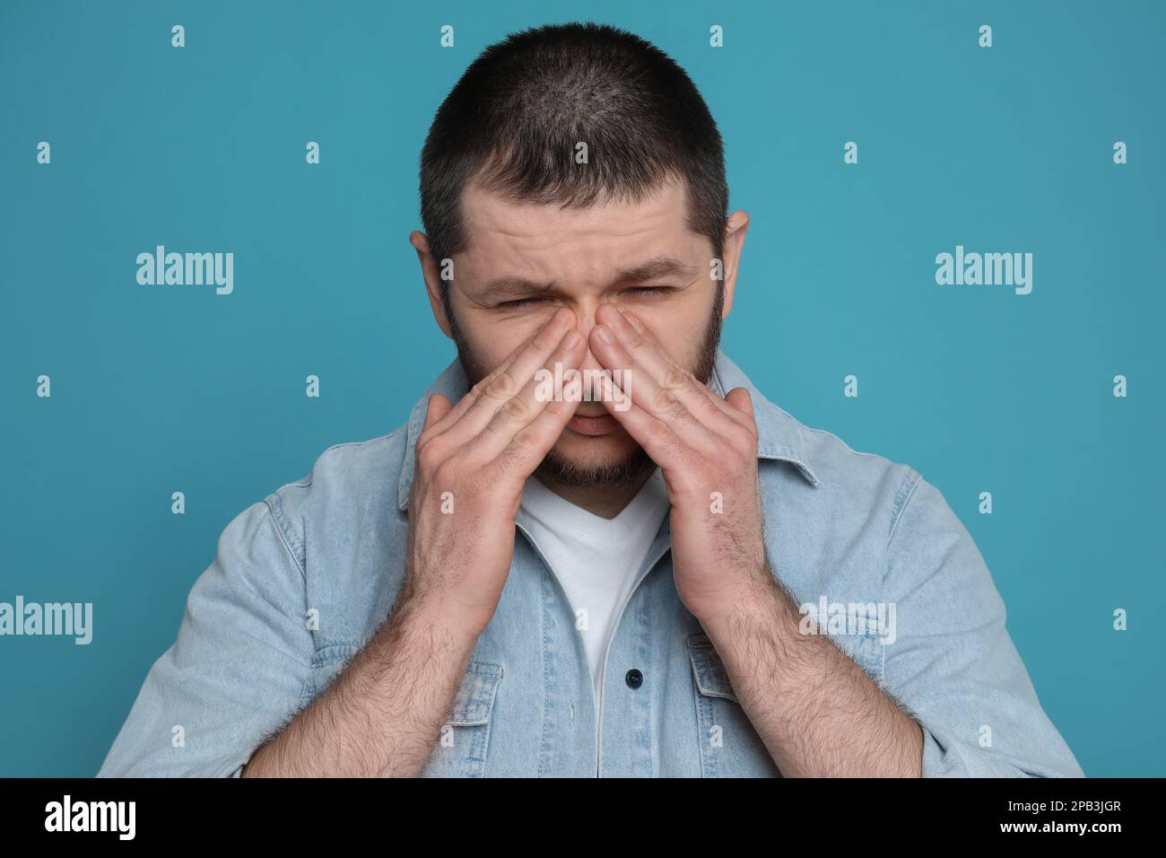 Uomo che soffre di mal di testa su sfondo azzurro Foto Stock