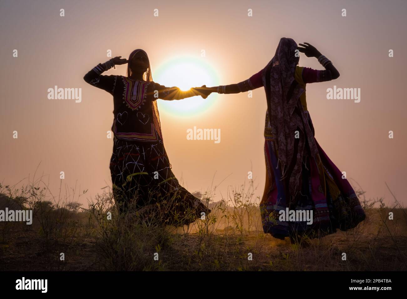 Due donne zingare in abiti danza di fronte al sole di setting, Pushkar Camel Fair, Pushkar, Rajasthan, India Foto Stock