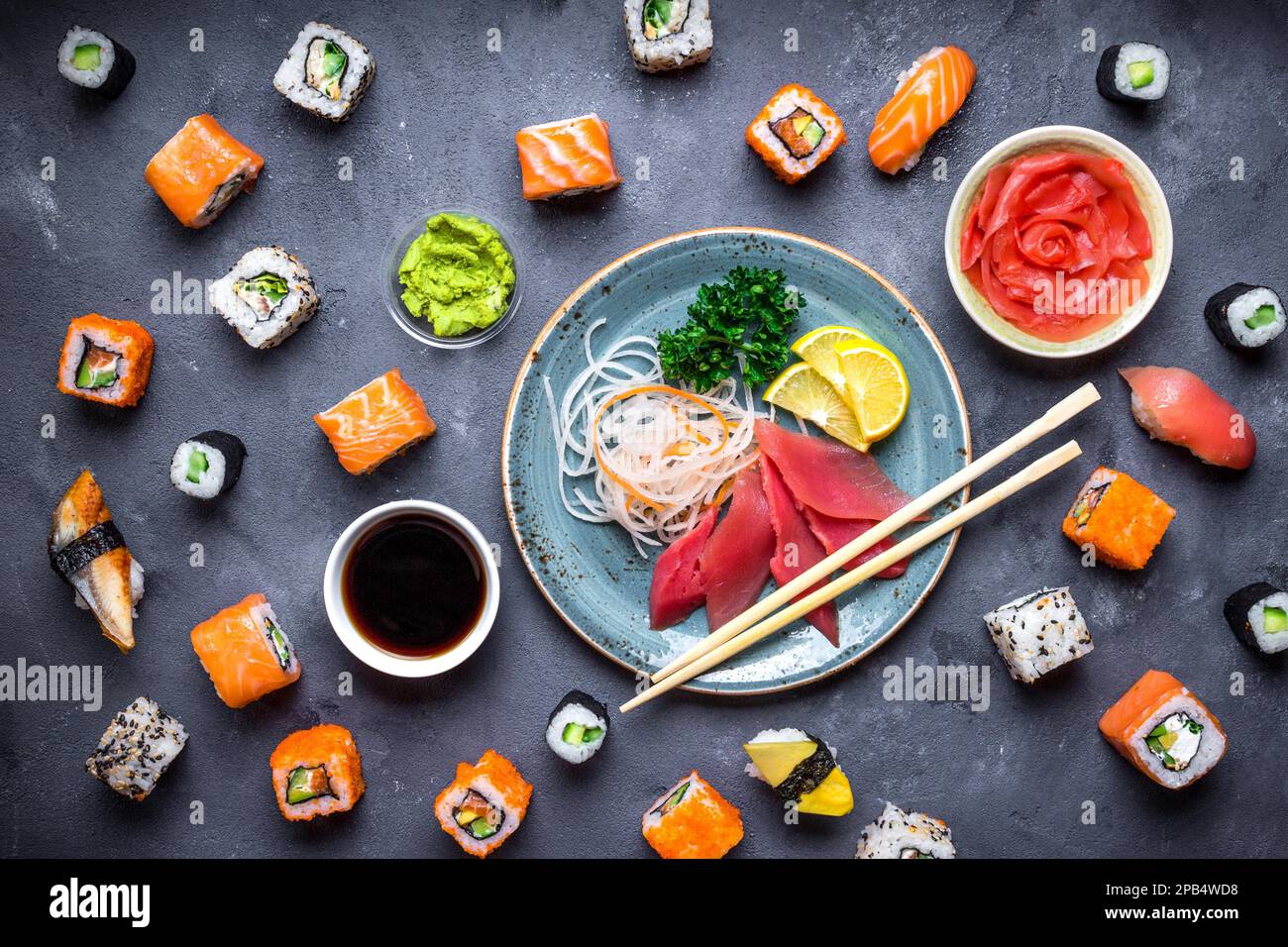 Sushi giapponese su uno sfondo rustico scuro. Sushi, sashimi, nigiri, maki, zenzero sottaceto, wasabi, salsa di soia. Sushi impostato su un tavolo. Vista dall'alto. ASI Foto Stock