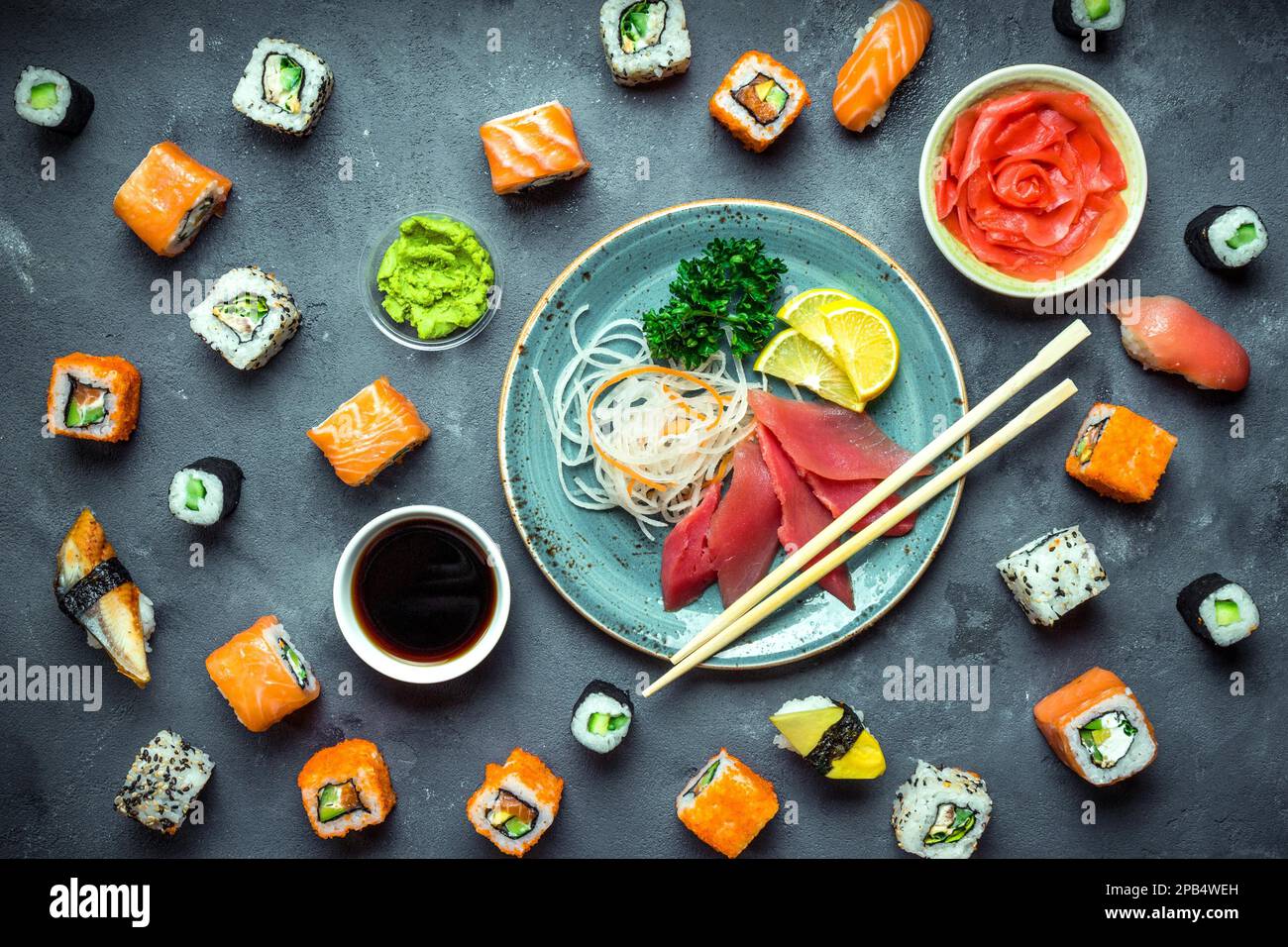 Sushi giapponese su sfondo rustico scuro. Sushi, sashimi, nigiri, maki, zenzero sottaceto, wasabi, salsa di soia. Sushi impostato su un tavolo. Vista dall'alto. Asiatico Foto Stock