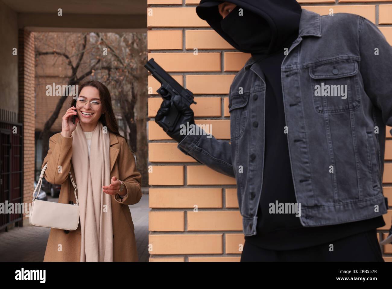 Criminale con la pistola che si nasconde dietro il muro e in attesa di vittima vicino vicolo Foto Stock