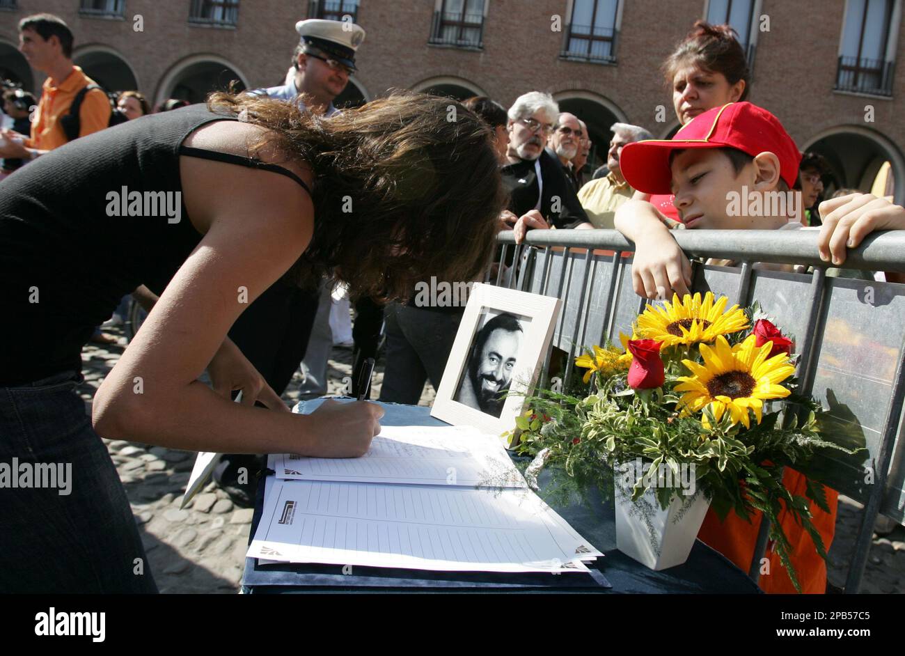 People sign their name in a condolence book outside Modena's Duomo cathedral where late Italian tenor Luciano Pavarotti is laying in state, northern Italy, Saturday, Sept. 8, 2007. Recordings of Pavarotti's voice boomed out in Modena's main piazza on Saturday as mourners waited to pay their final respects to the tenor before an invitation-only funeral in his hometown's cathedral. The Italian tenor died Thursday Sept. 6 in his home. He was 71. (AP Photo/Alessandra Tarantino) Foto Stock