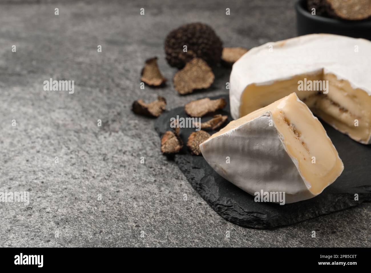 Delizioso formaggio al tartufo su tavola grigia, primo piano. Spazio per il testo Foto Stock