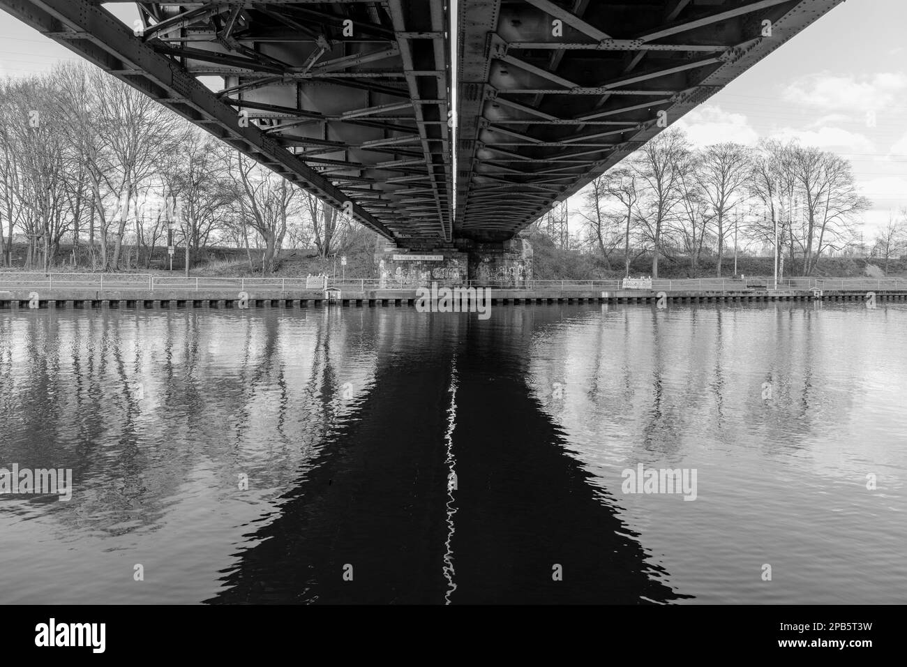 Sotto il ponte ferroviario su un canale di Oberhausen, Germania. Foto scattata alla luce del giorno in bianco e nero Foto Stock