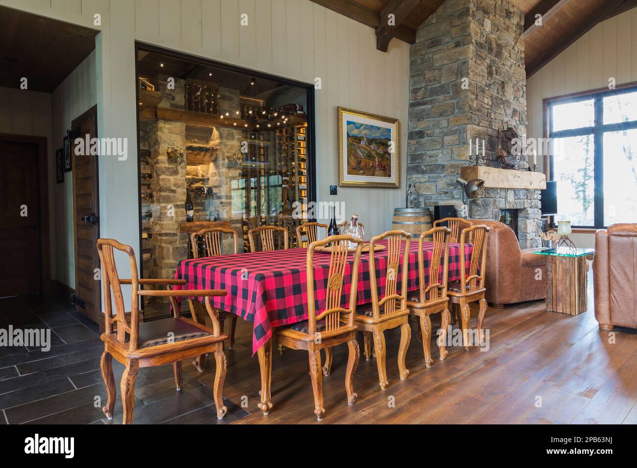 Tavolo in teak con sedie alte sul retro e pavimenti in legno di pino rosso macchiato nell'area della sala da pranzo all'interno della casa con struttura in legno ibrido. Foto Stock