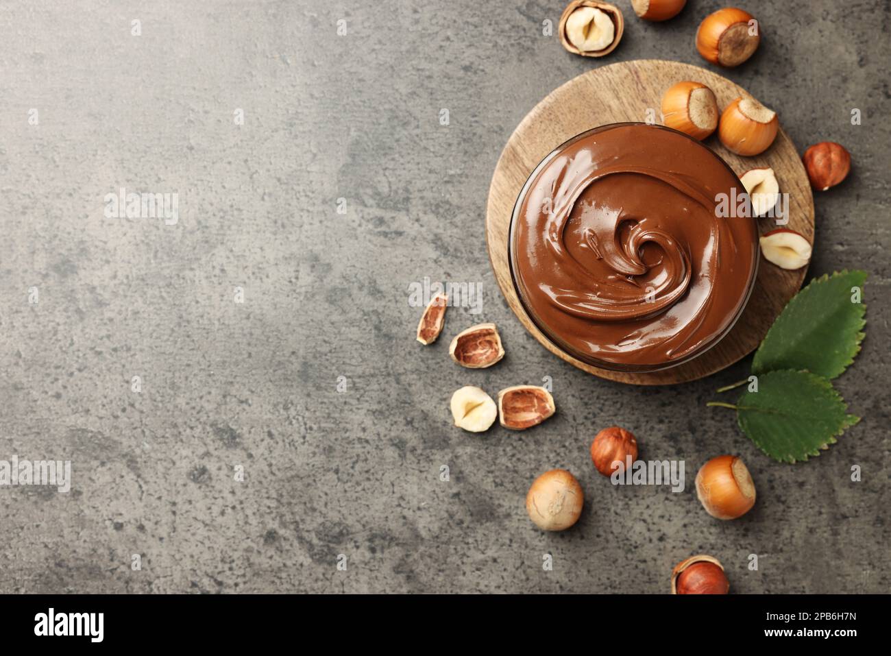 Saporito cioccolato nocciola spalmata e noci su tavola grigia, piatto. Spazio per il testo Foto Stock