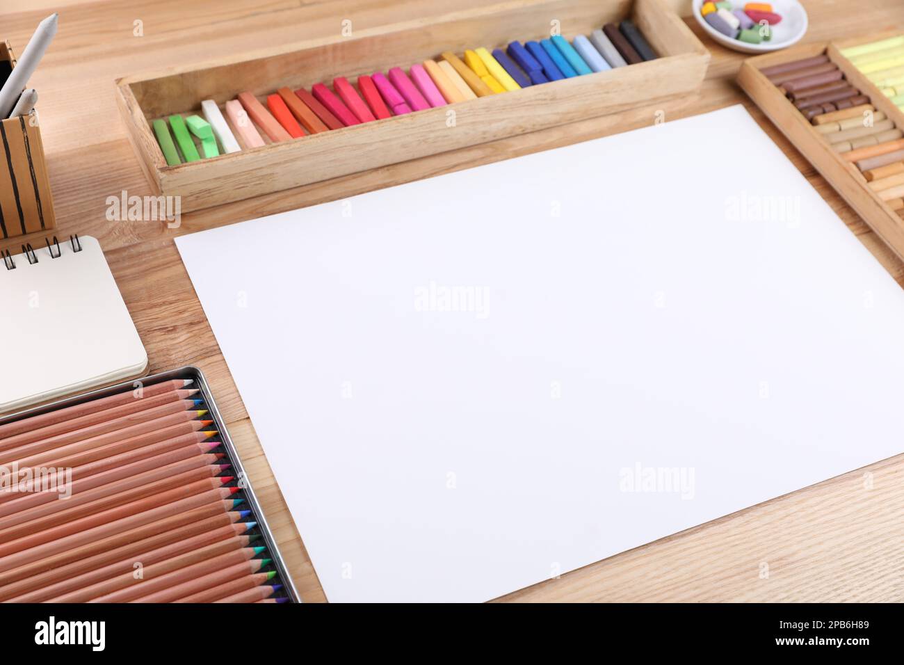 Carta bianca, pastelli morbidi e matite da disegno su tavola di legno sul  posto di lavoro dell'artista. Spazio per il design Foto stock - Alamy