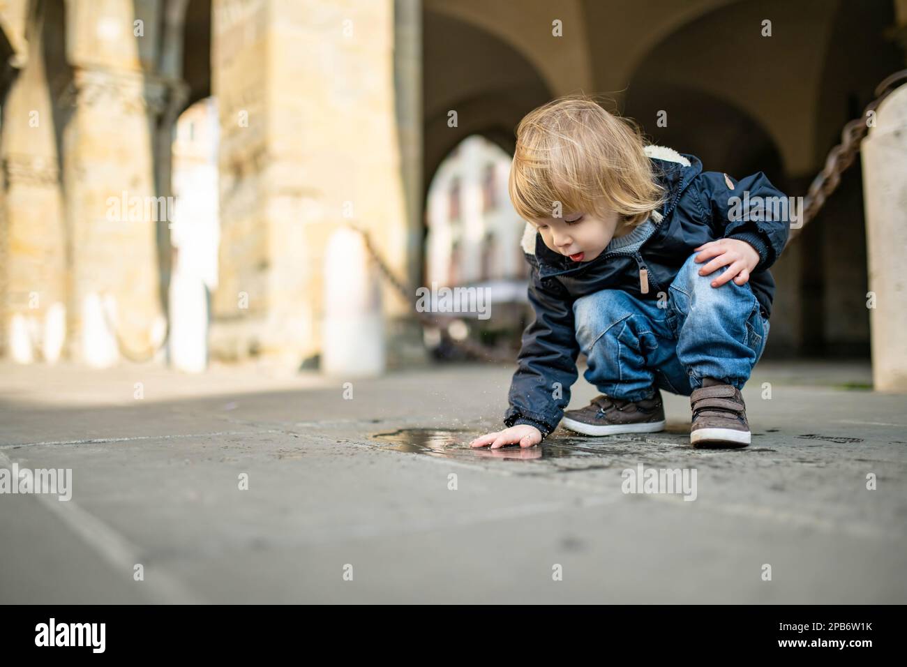 Carino bambino che gioca in una pozza sulla strada di Bergamo. Piccolo bambino che si diverte a esplorare Città alta, nell'alto quartiere di Bergamo. Bergamo, lo Foto Stock