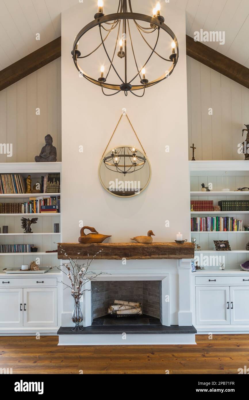 Caminetto decorativo dipinto di bianco tra librerie e pavimenti in legno di pino rosso nella camera da letto principale all'interno della casa con struttura in legno ibrido. Foto Stock