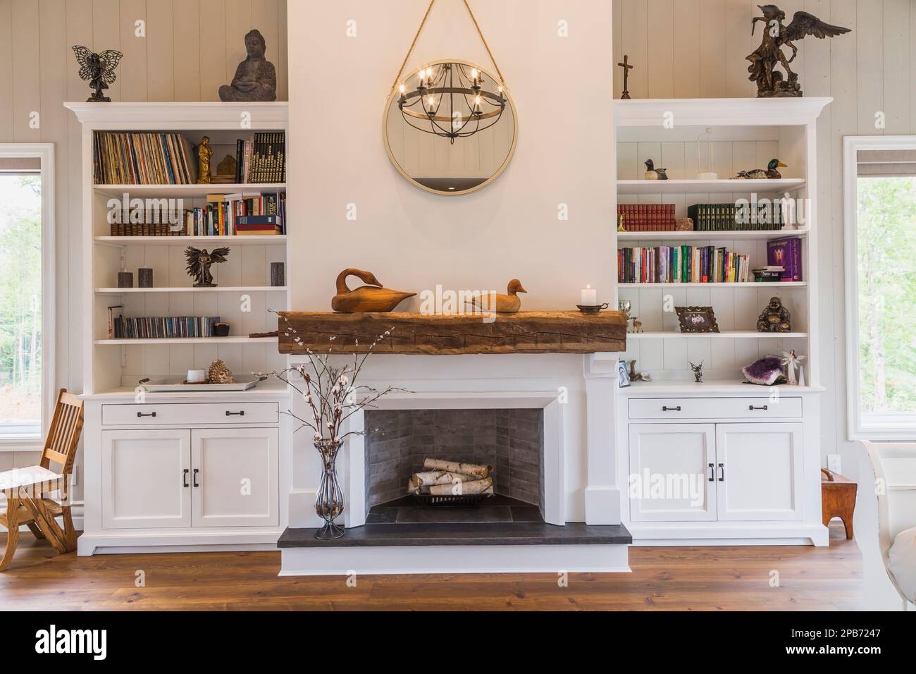 Caminetto decorativo dipinto di bianco tra librerie e pavimenti in legno di pino rosso nella camera da letto principale all'interno della casa con struttura in legno ibrido. Foto Stock