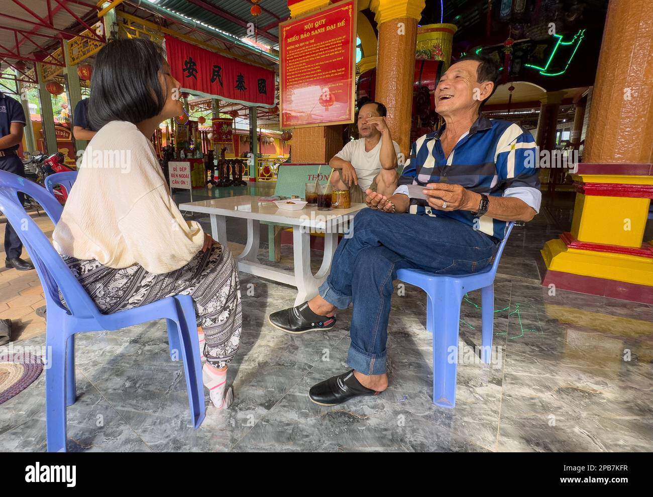 Un cassiere di fortuna in un tempio taoista a Tan Chau nel delta del Mekong del Vietnam parla con una donna vietnamita. Foto Stock