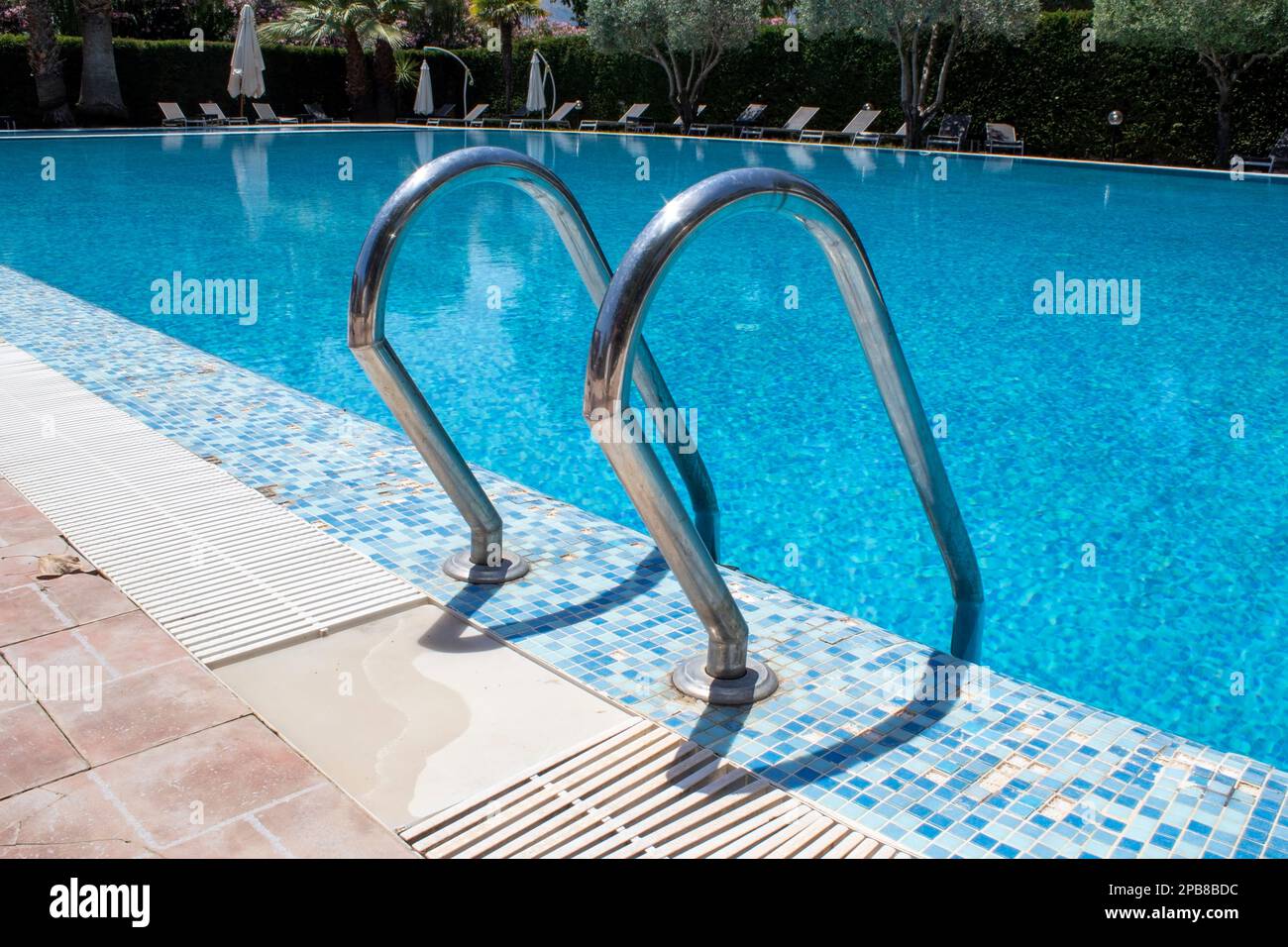 Gradini in una piscina d'acqua. Piscina all'aperto con corrimano presso il resort il giorno del sole. Foto Stock