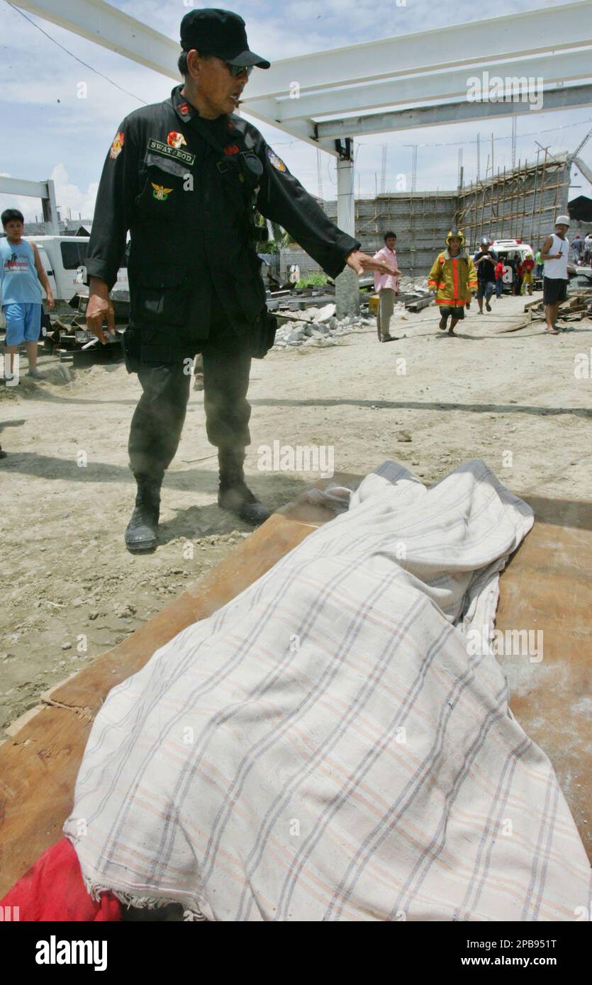 A police officer stands beside the body of a worker pulled from the rubble Thursday, Aug. 2, 2007, in Paranaque south of Manila, Philippines after a concrete wall of a building under construction collapsed. Some 15 others were reported injured. (AP Photo/Pat Roque) Foto Stock