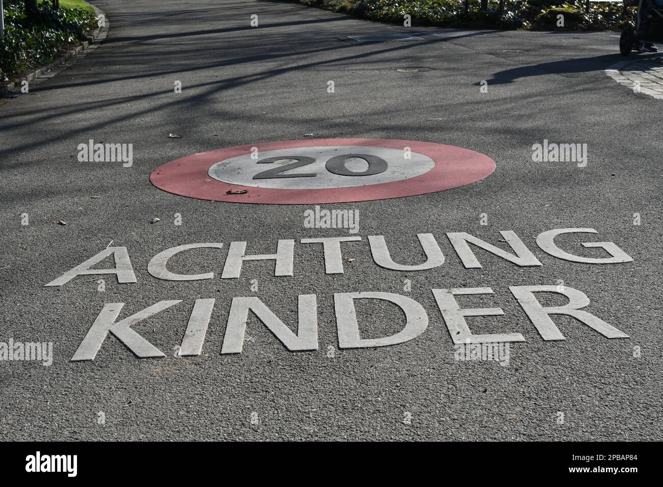 Strada con cartello per limite di velocità 20 km all'ora e iscrizione in lingua tedesca che dice attenzione ai bambini. Foto Stock