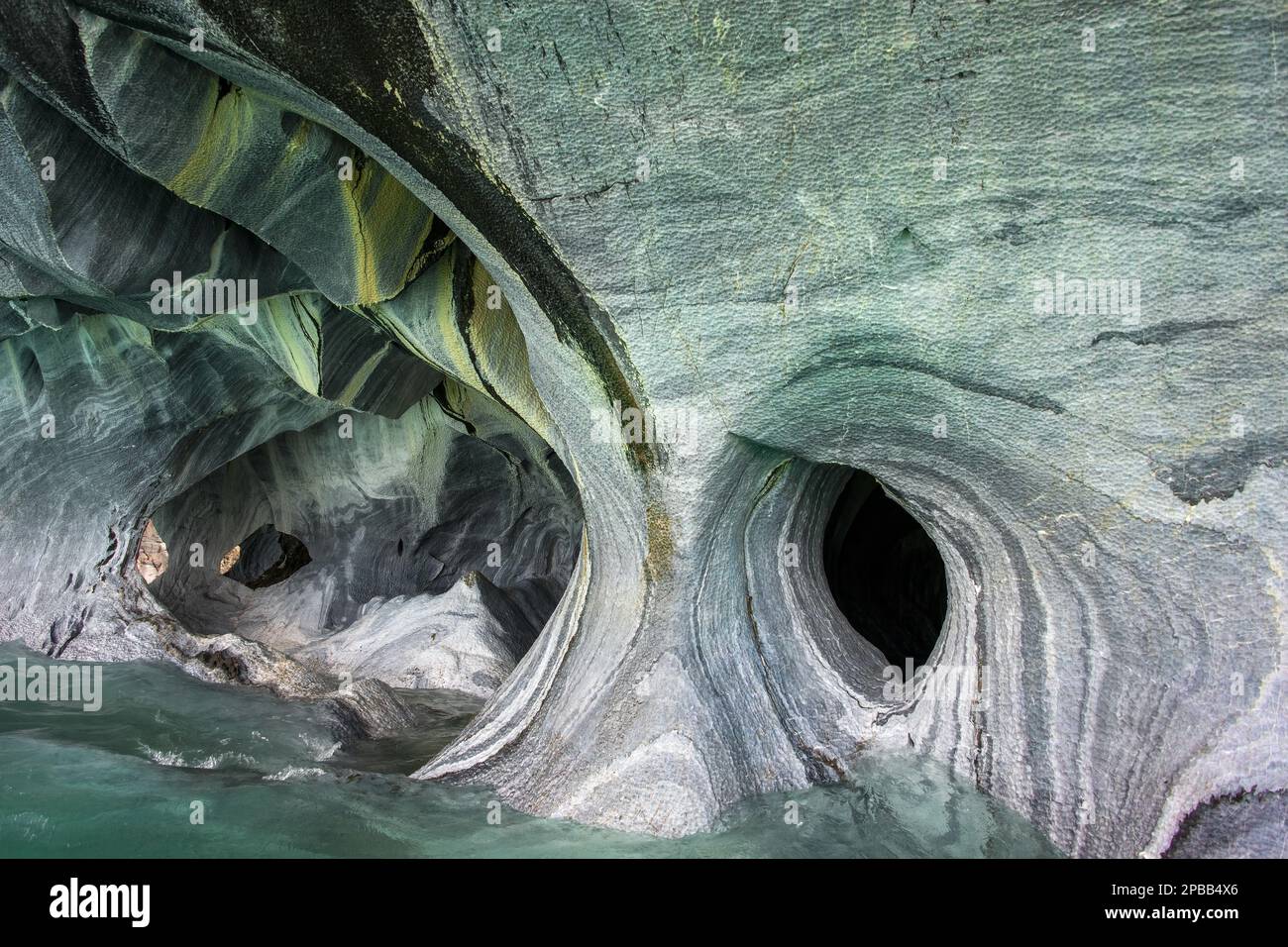 Superfici erose e fori nelle Grotte di marmo con riflessi dalle acque turchesi del Lago General Carrera, Patagonia Foto Stock