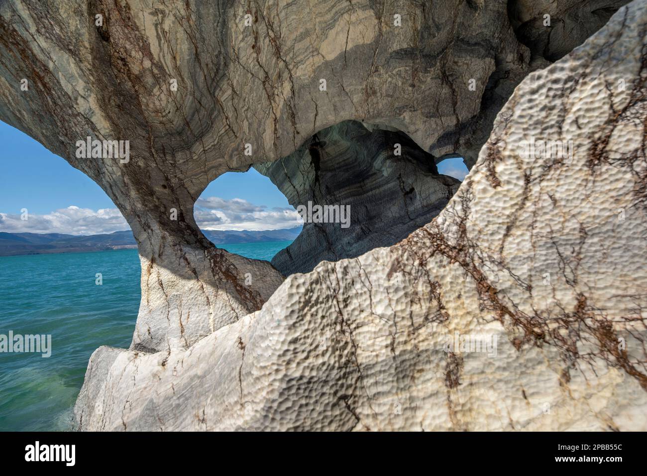 Dai un'occhiata attraverso il marmo eroso alle montagne lontane, alle grotte di marmo, al Lago General Carrera, alla Patagonia Foto Stock