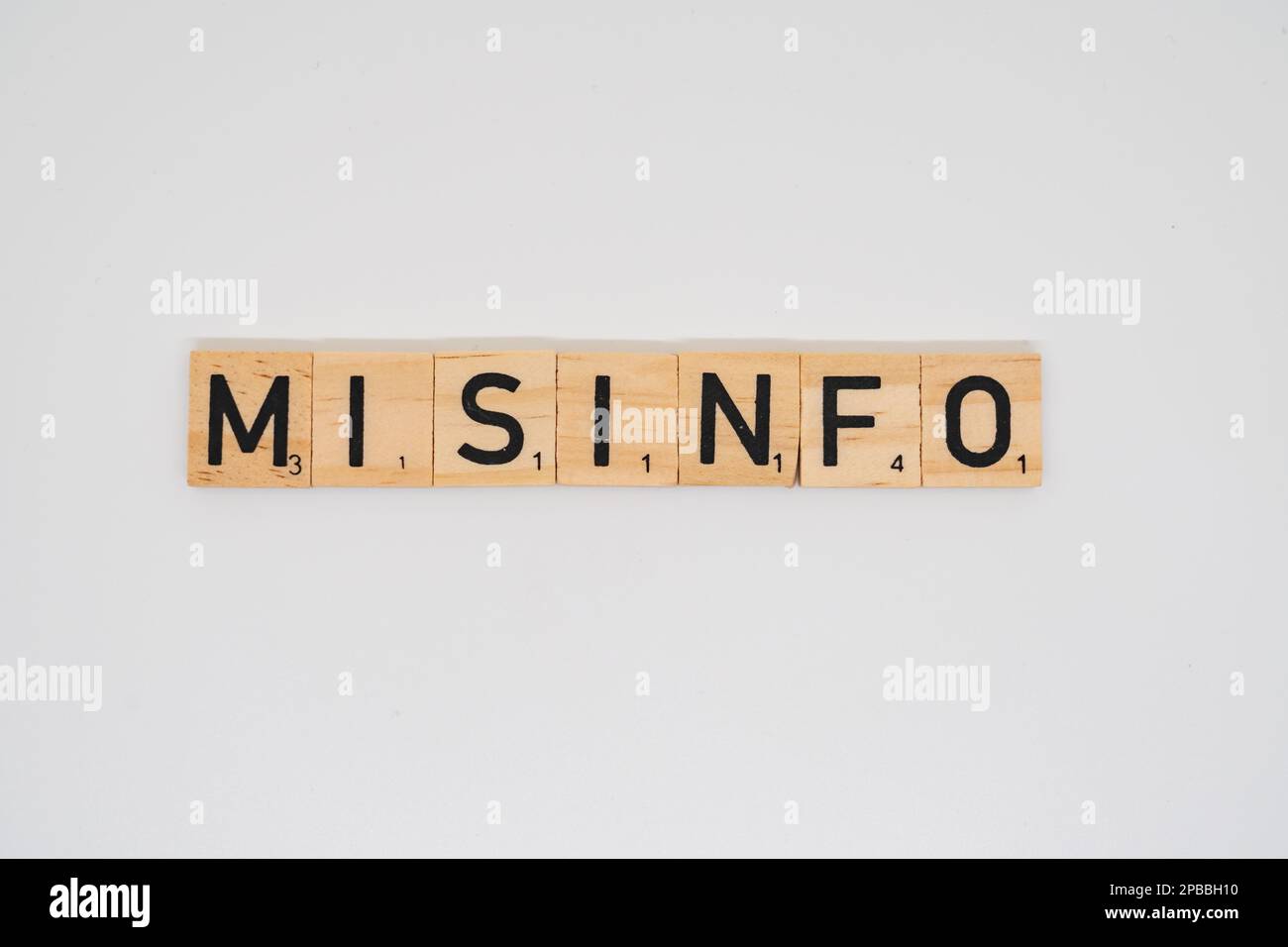 Il titolo di legno che ortografia la parola misinfo isolato su uno sfondo bianco Foto Stock