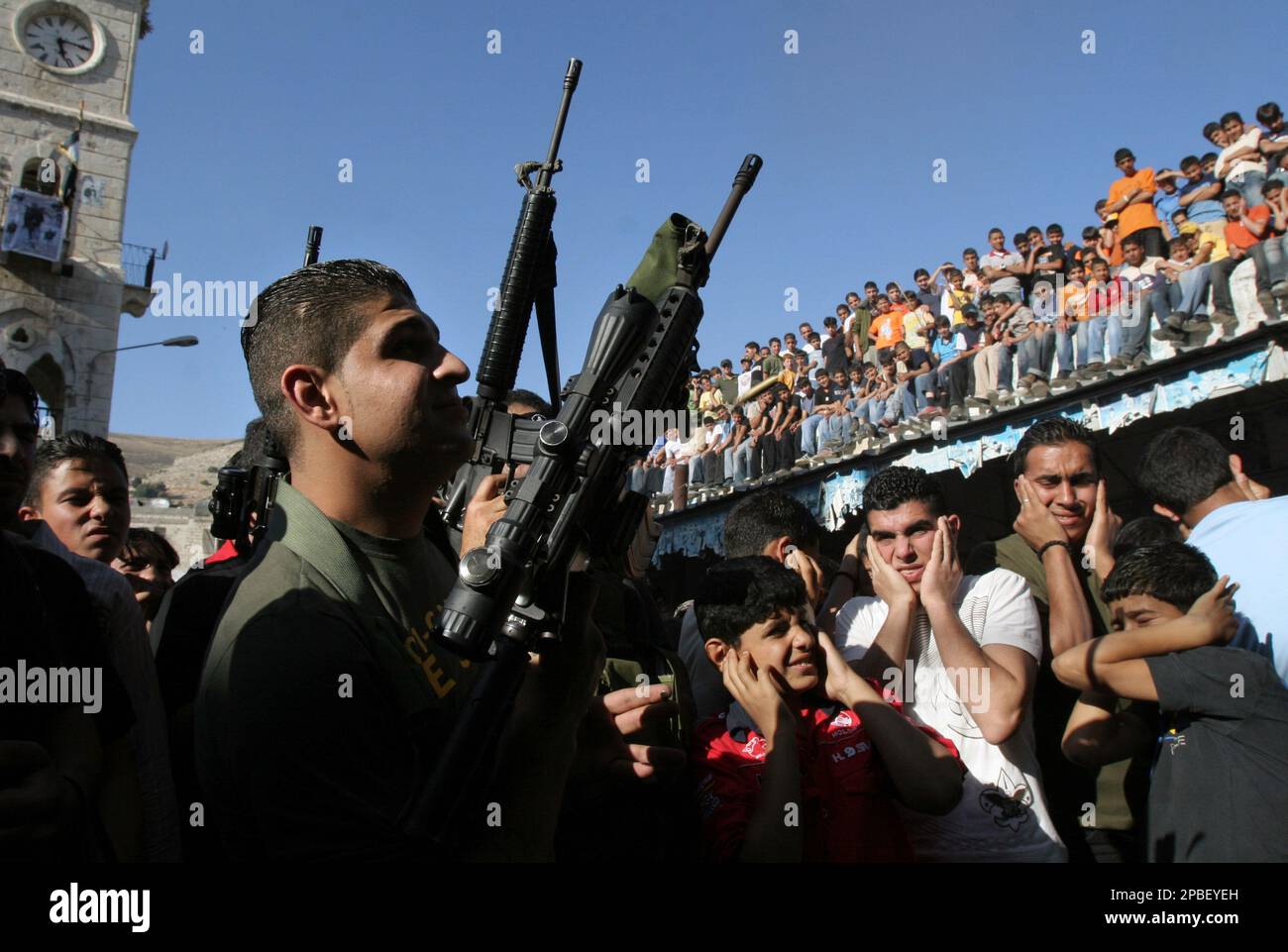 Palestinian youths cover their ears as militants from the Al Aqsa Martyrs Brigades, a militia linked to the Fatah Movement prepare to fire their weapons in the air during a rally to mark the death of its members killed over the years in the conflict with Israel, in the West Bank city of Nablus, Friday, June 1, 2007. Israeli and Palestinian leaders are to meet next week in the Palestinian territories for the first time in a bid to restore a shattered cease-fire in the Gaza Strip, a senior Palestinian official said. (AP Photo/Nasser Ishtayeh) Foto Stock