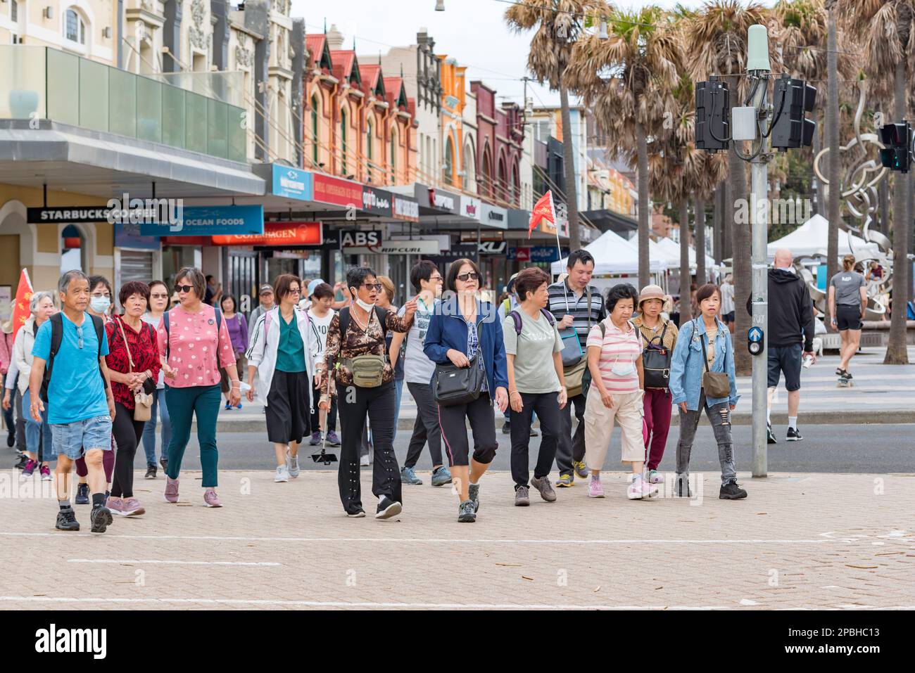 Un grande gruppo di turisti cinesi che camminano dal corso verso Manly Beach la domenica a Sydney, Australia Foto Stock