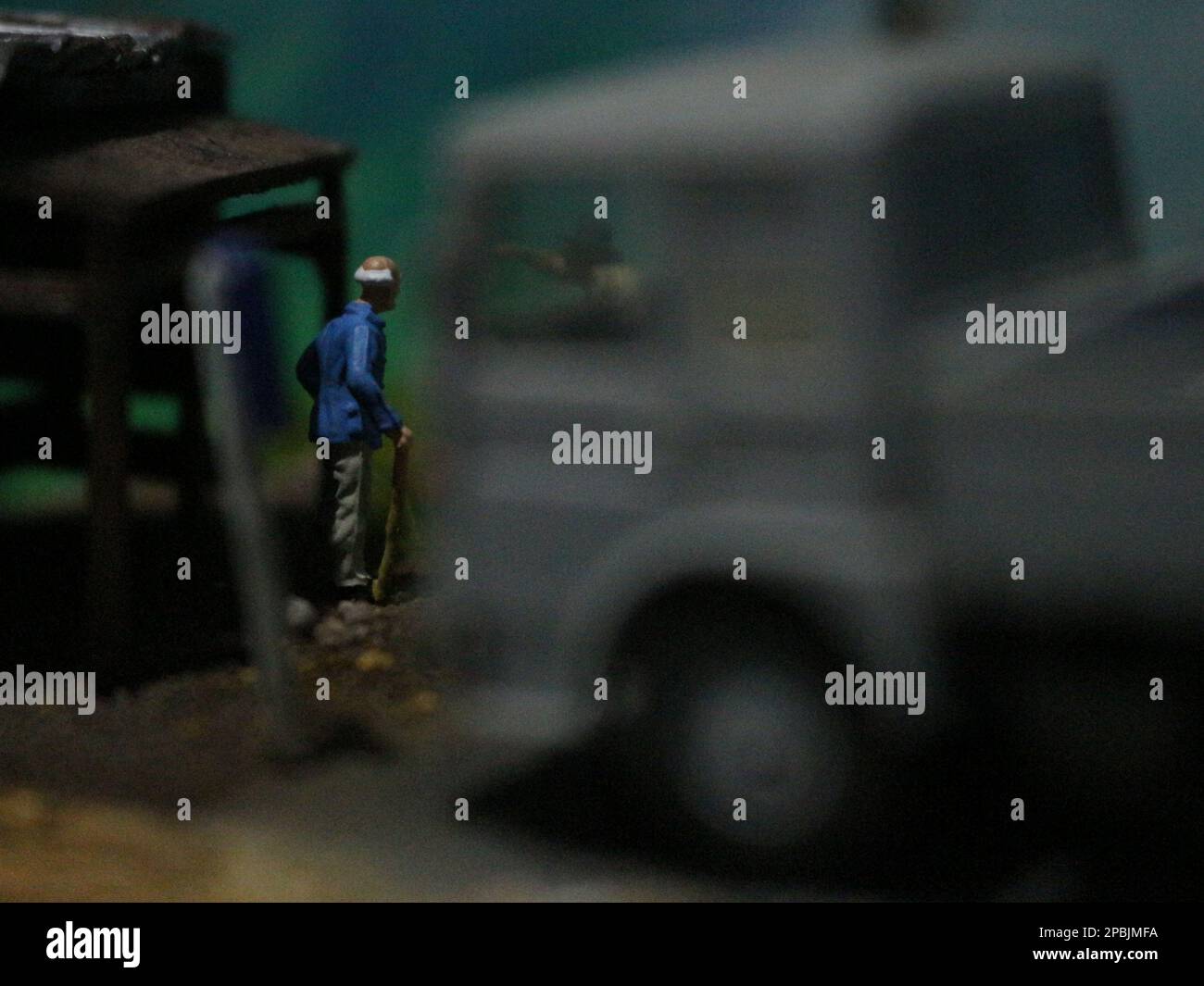 un primo piano di una figura in miniatura di un vecchio che parla con altre persone in un vecchio edificio a lato della strada. Foto Stock