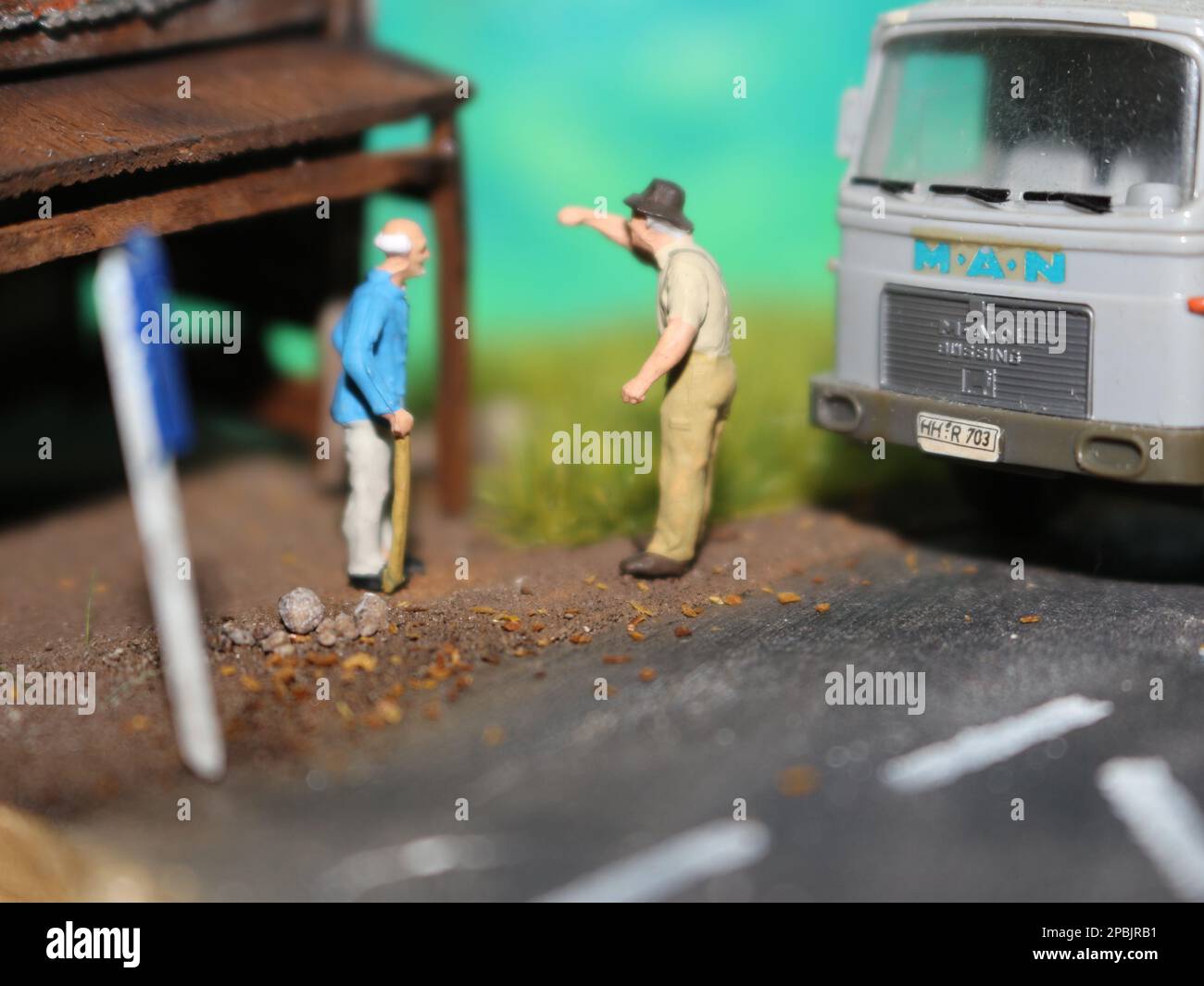 un primo piano di una figura in miniatura di un vecchio che parla con altre persone in un vecchio edificio a lato della strada. Foto Stock