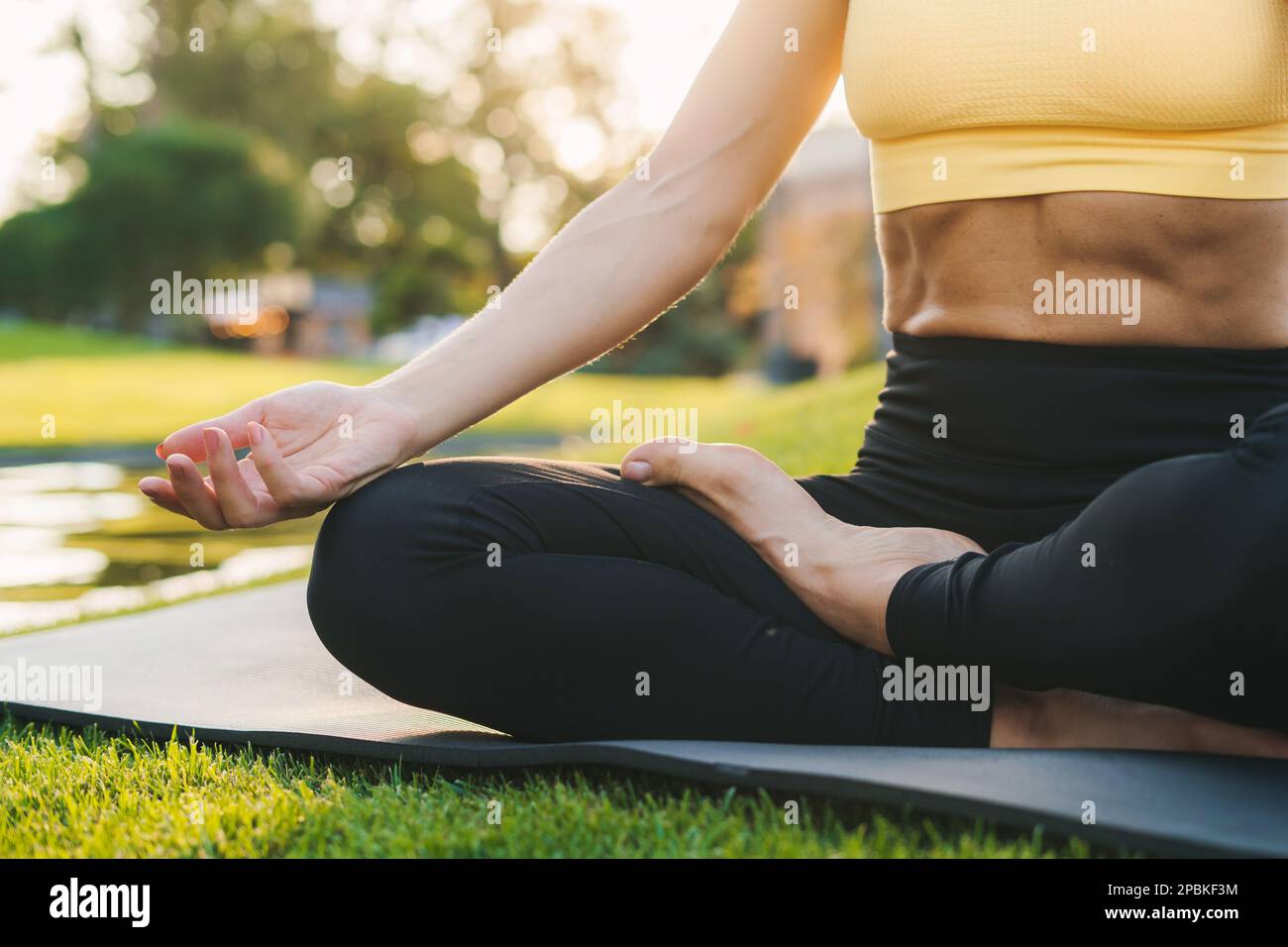 Primo piano ritratto delle mani di una donna sportiva caucasica in maglioni sportivi rilassanti, meditando sul tappetino fitness nel parco pubblico all'aperto. Sano attivo Foto Stock