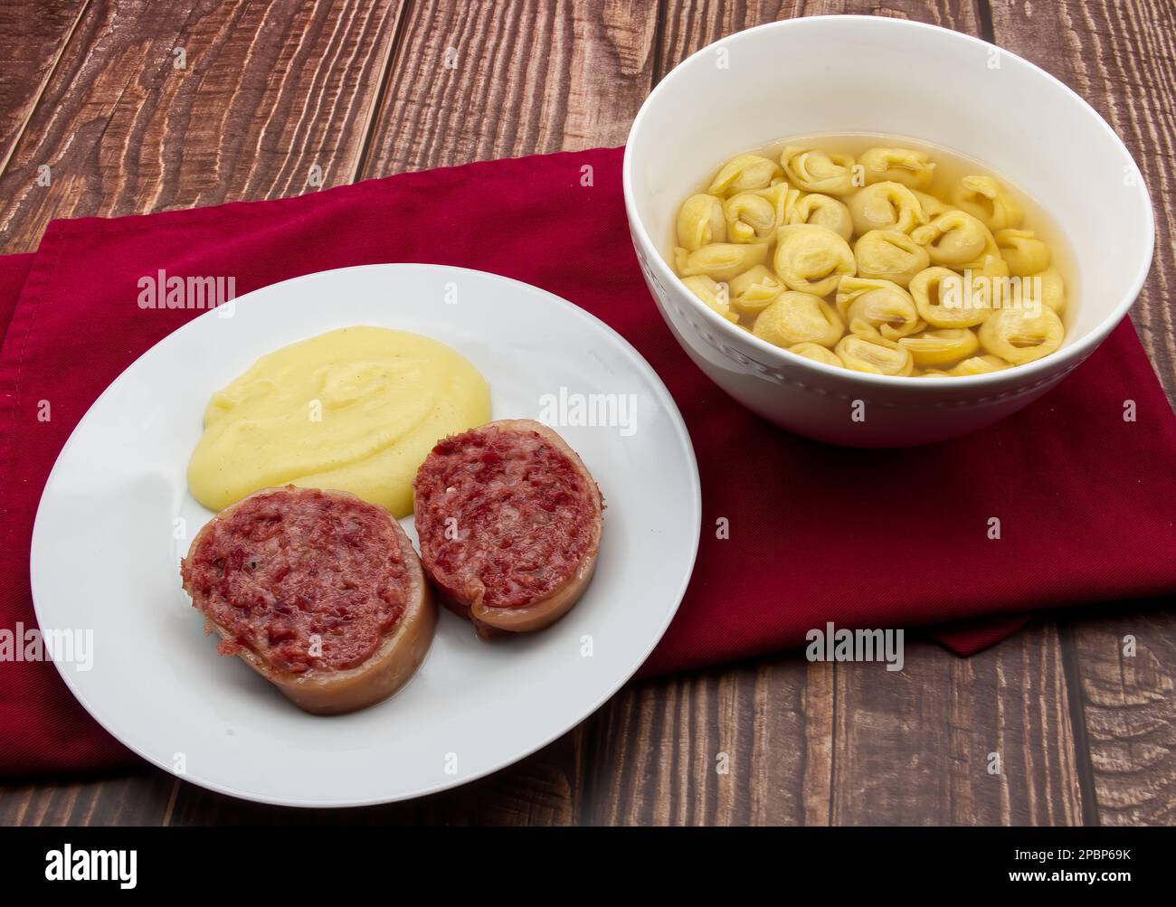 Fette di salsicce tradizionali italiane Zampone di Modena con purè di patate e un piatto di pasta tortellini. Foto Stock