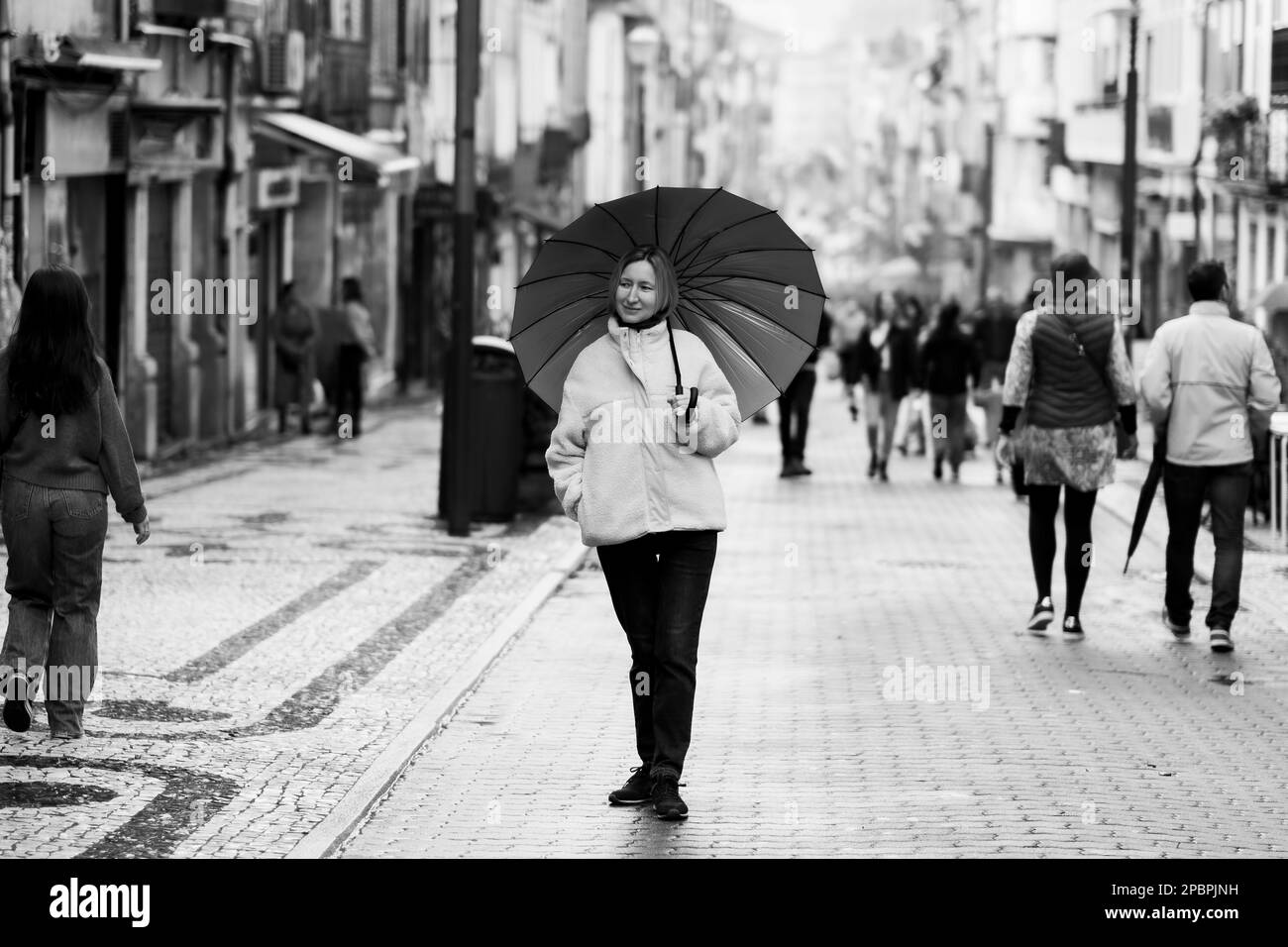 Una donna con un ombrello sulla strada principale di Santa-Catarina a Porto, Portogallo. Foto in bianco e nero. Foto Stock