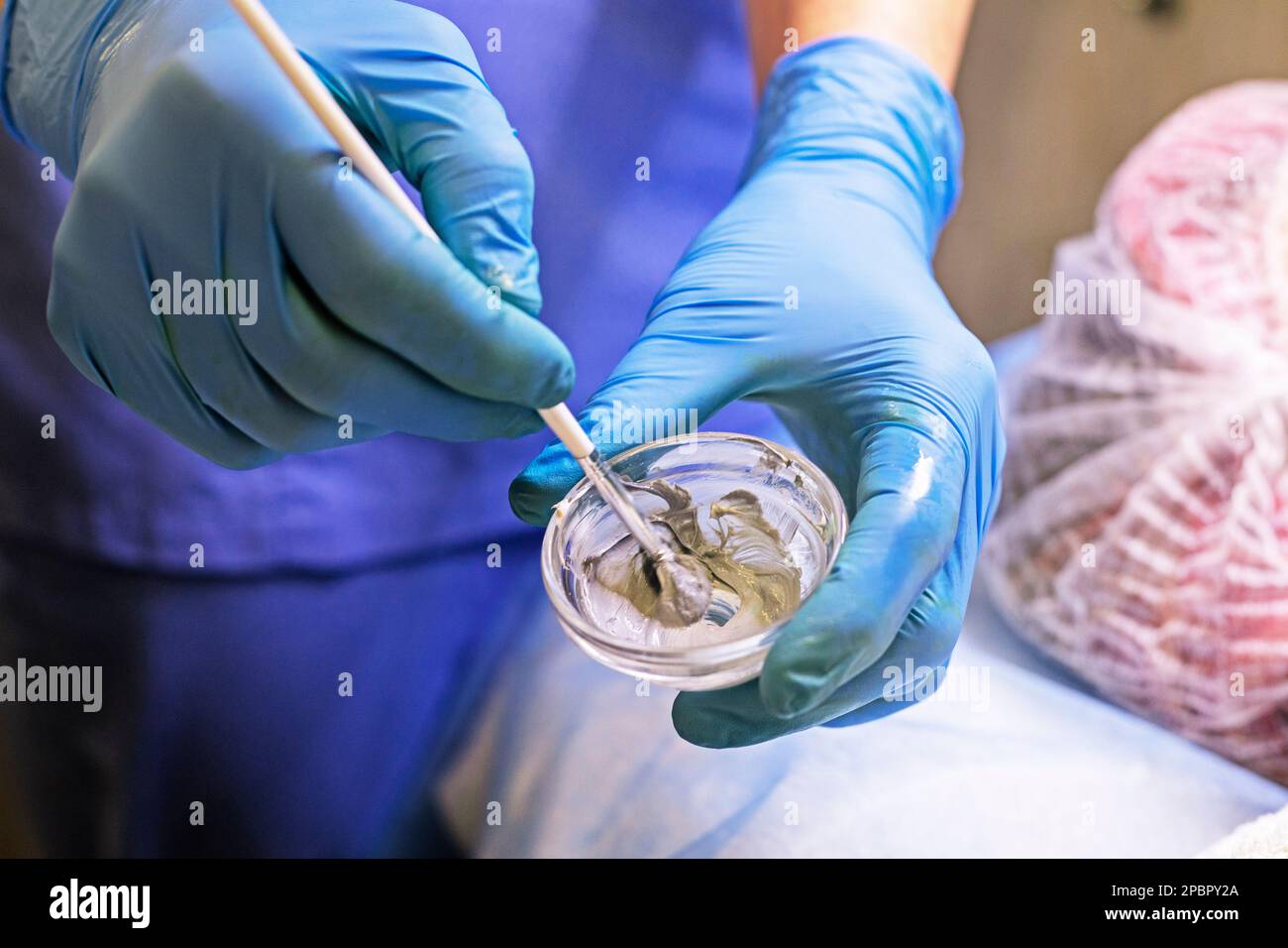 estetista agita in un contenitore di vetro una sostanza medicinale per una maschera facciale Foto Stock