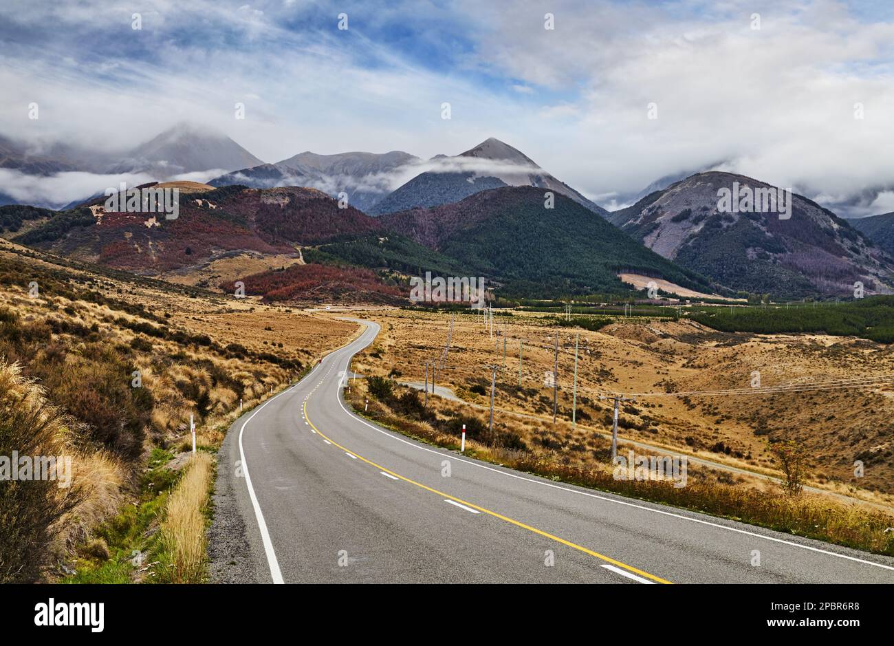 Paesaggio montano con strada e cielo nuvoloso, Arthur's Pass, Alpi meridionali, Nuova Zelanda Foto Stock