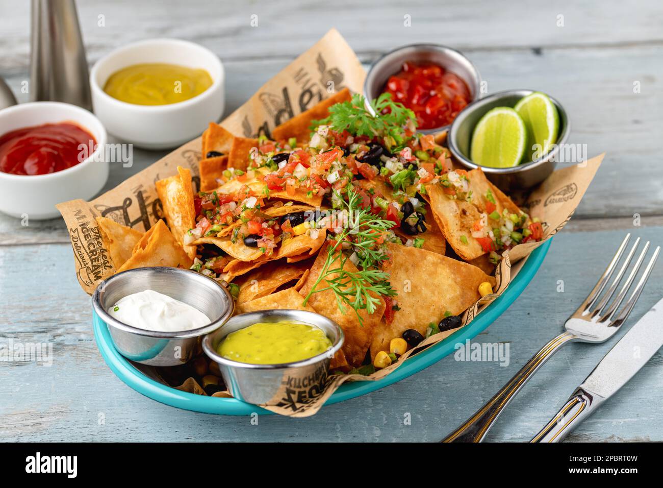 Tradizionale cibo messicano nachos con salse varie su tavolo di legno Foto Stock