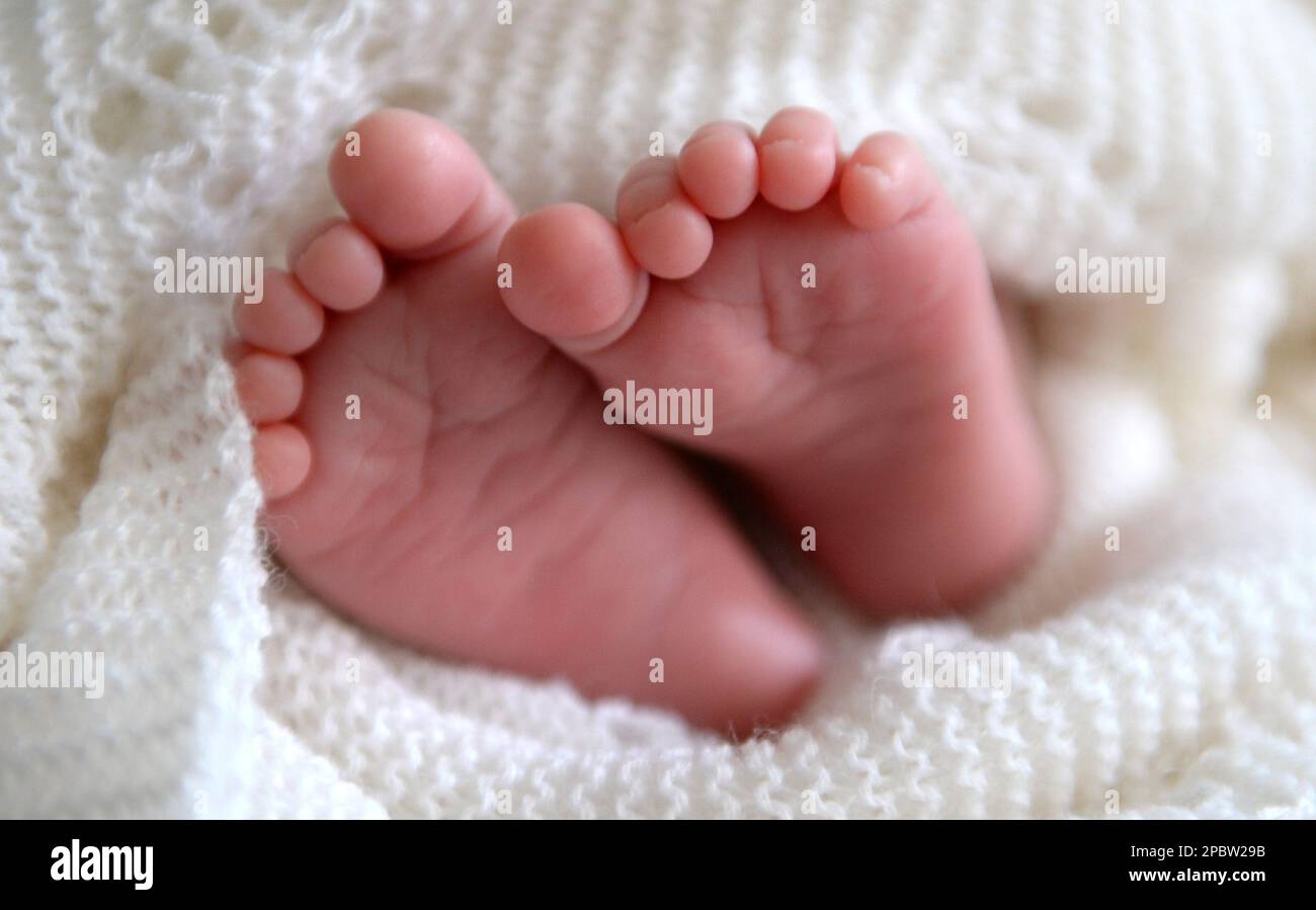 Foto del file datata 11/07/2014 di un neonato sono visibili i piedi che sbirciano da uno scialle. Gli esperti principali stanno chiedendo ai genitori di essere dato consiglio di sicurezza circa co-sonno con i loro bambini dopo che la ricerca ha rivelato che la maggior parte lo fa ad un certo punto. Un sondaggio di 3.402 nuovi genitori per la beneficenza Lullaby Trust, che aumenta la consapevolezza della sindrome da morte infantile improvvisa (SIDS), ha scoperto che nove genitori su 10 hanno dormito accanto al loro bambino, ma solo quattro su 10 sono stati informati da un professionista sanitario come ridurre il rischio di morte in culla. Data di emissione: Lunedì 13 marzo 2023. Foto Stock