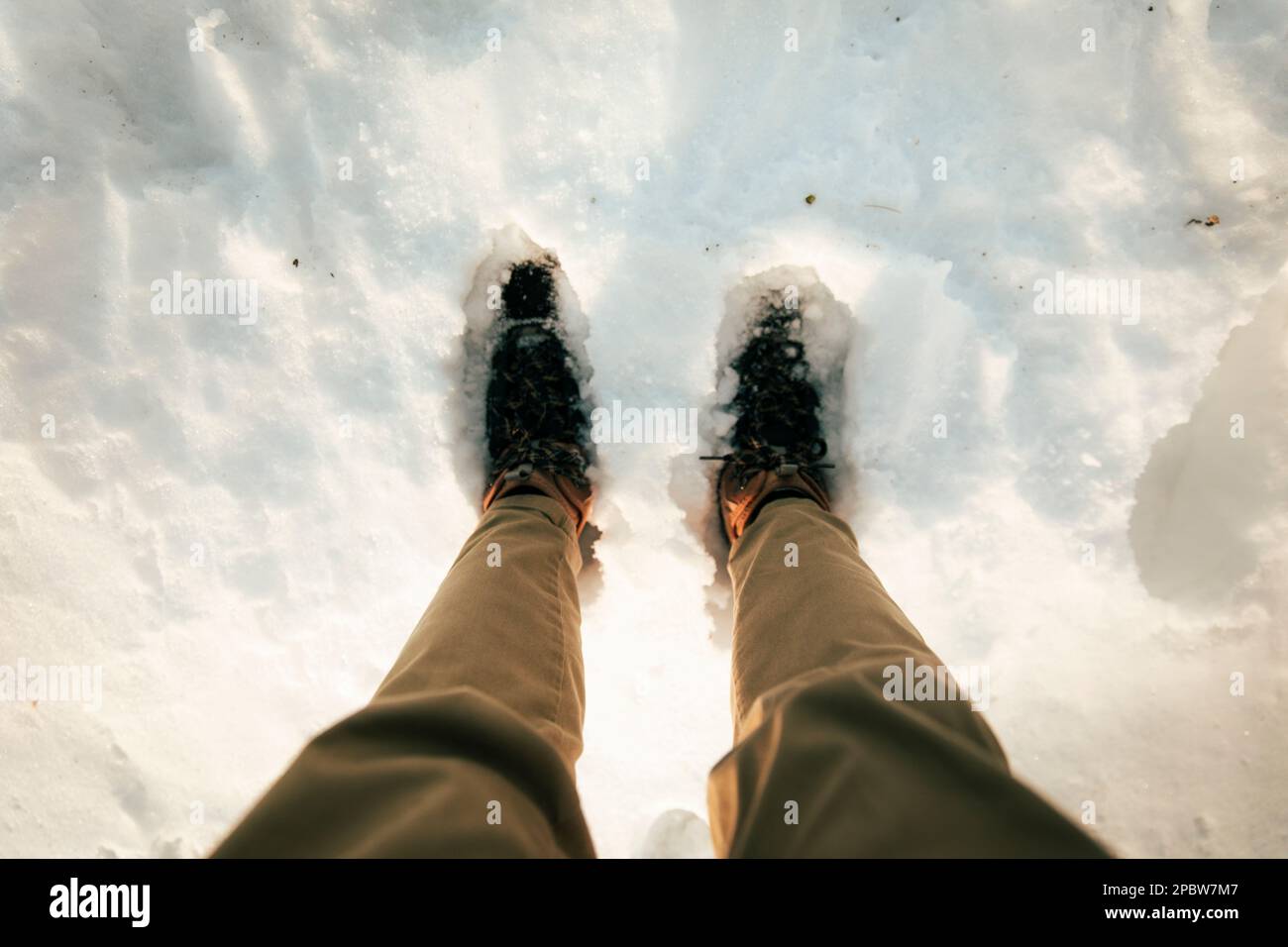 Gambe di un uomo con scarponi da trekking su un terreno pieno di neve Foto Stock