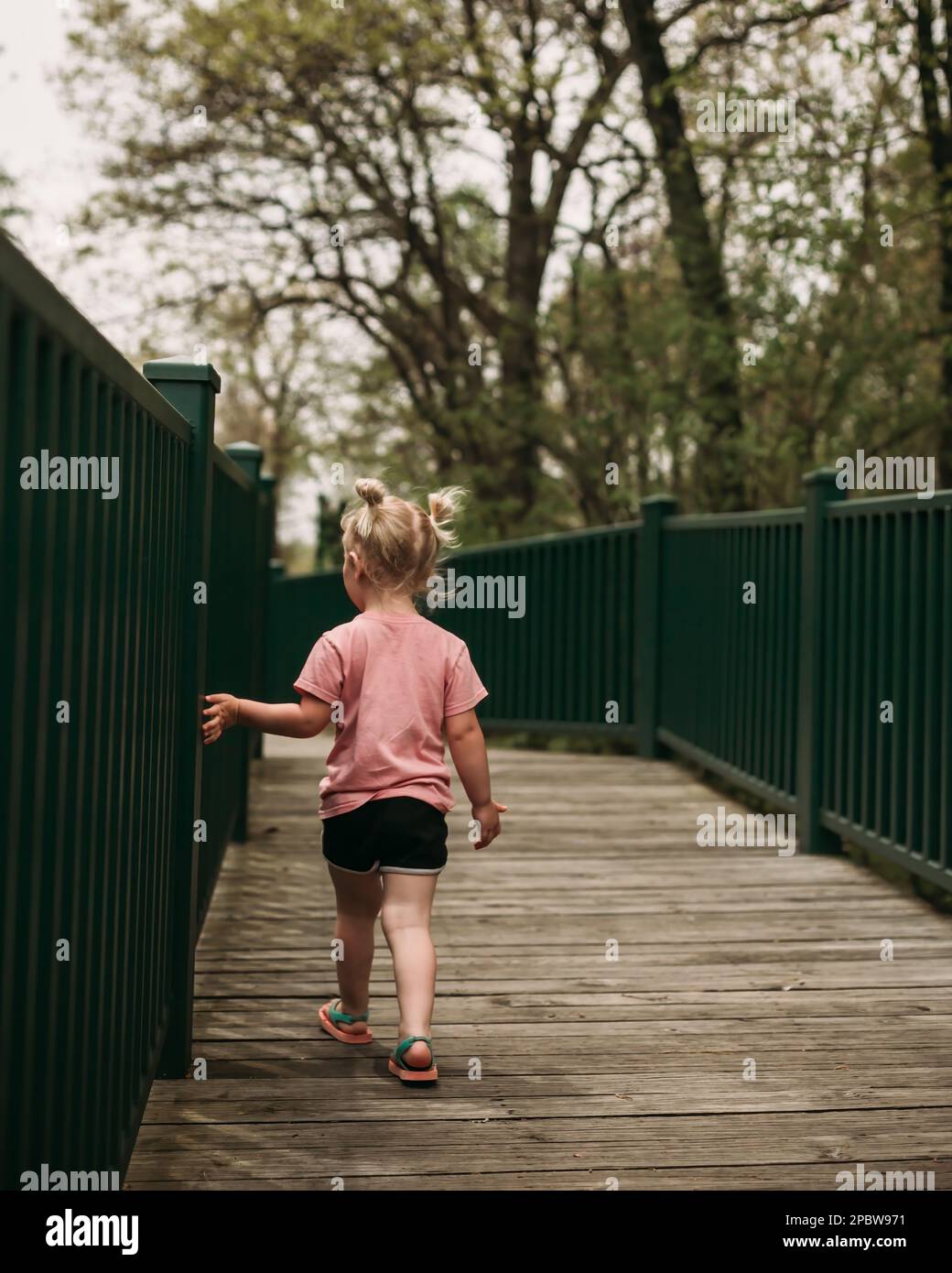 Bambino in giovane età che cammina sul ponte durante la passeggiata nella natura Foto Stock