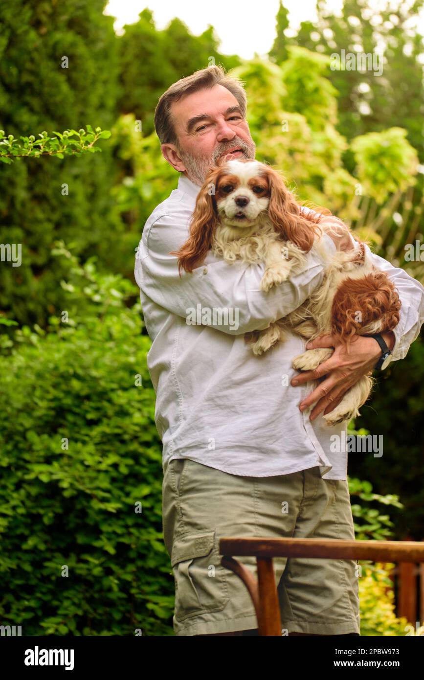 Ritratto di un uomo anziano con il cane in giardino. Foto Stock