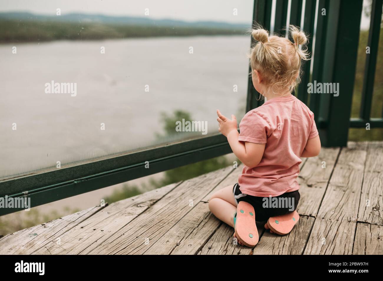 Bambino che guarda il fiume dalla vista Foto Stock