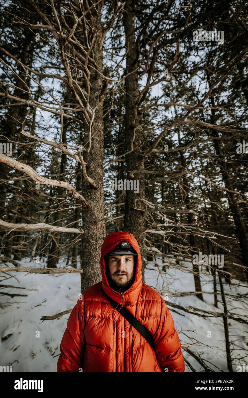 Ritratto di giovane uomo in inverno indossando giacca color arancio con cappuccio. Foto Stock