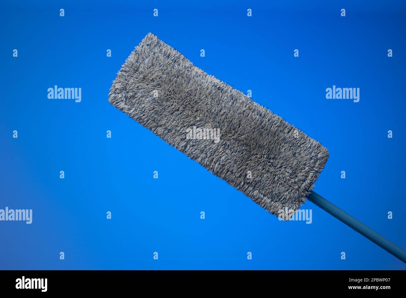Spazzolone generico in plastica con spugna tessile sporca. Primo piano ripresa in studio, isolata su sfondo blu. Foto Stock