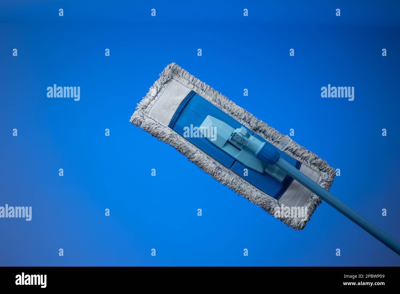 Spazzolone generico in plastica con spugna tessile sporca. Primo piano ripresa in studio, isolata su sfondo blu. Foto Stock