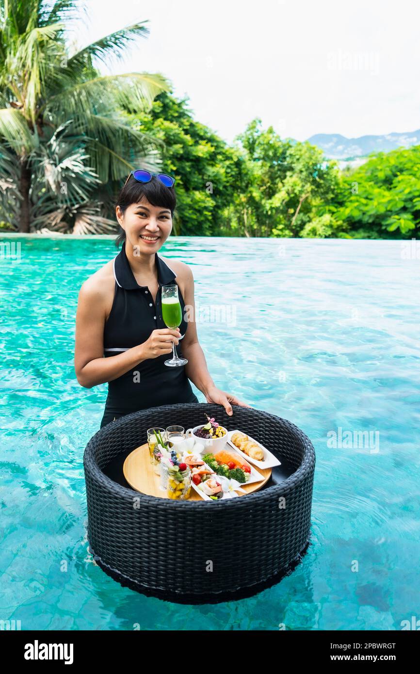 Bella donna gode di una colazione galleggiante in Thailandia Foto Stock