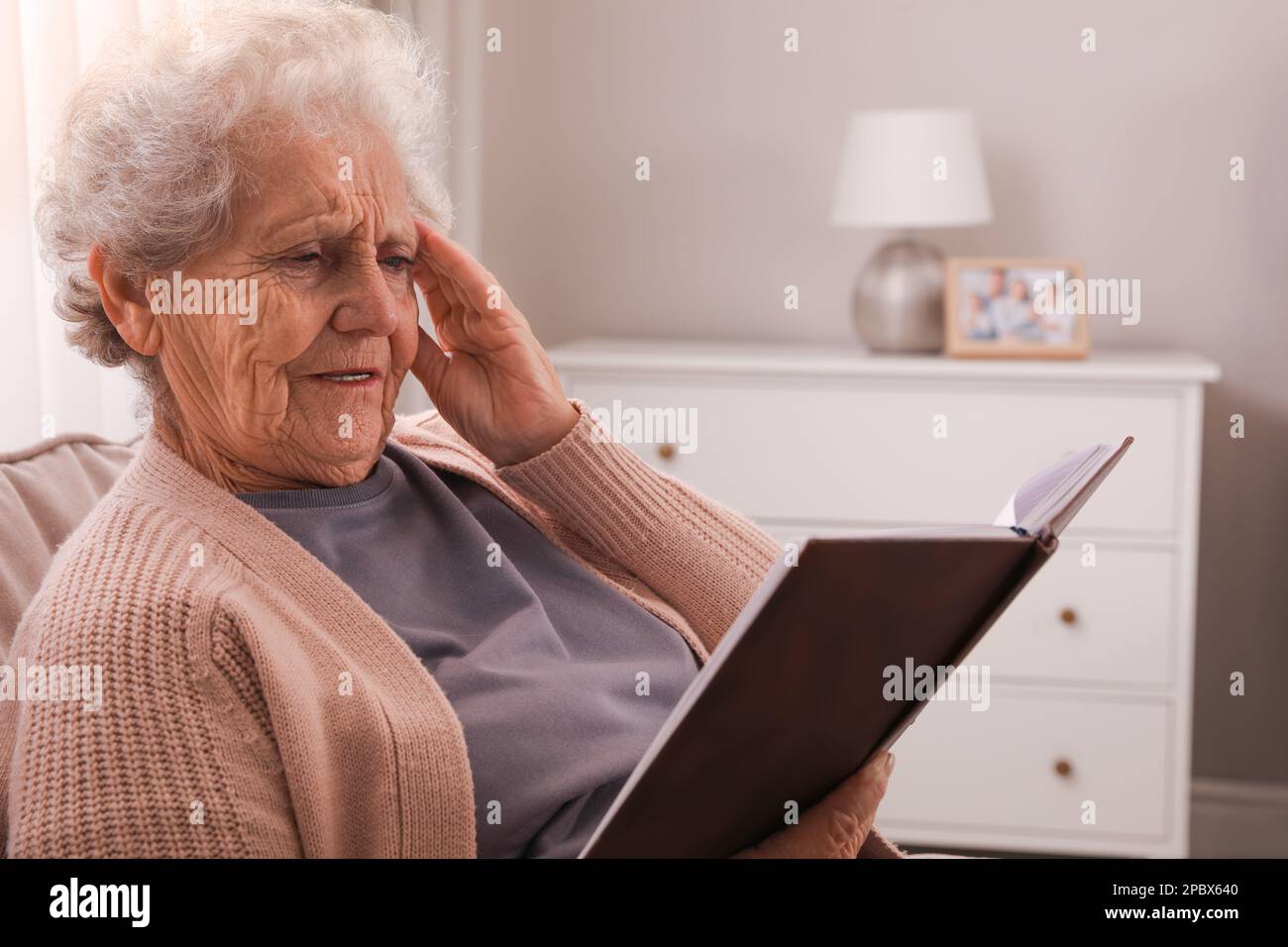 Donna anziana con notebook a casa. Compromissione della memoria correlata all'età Foto Stock