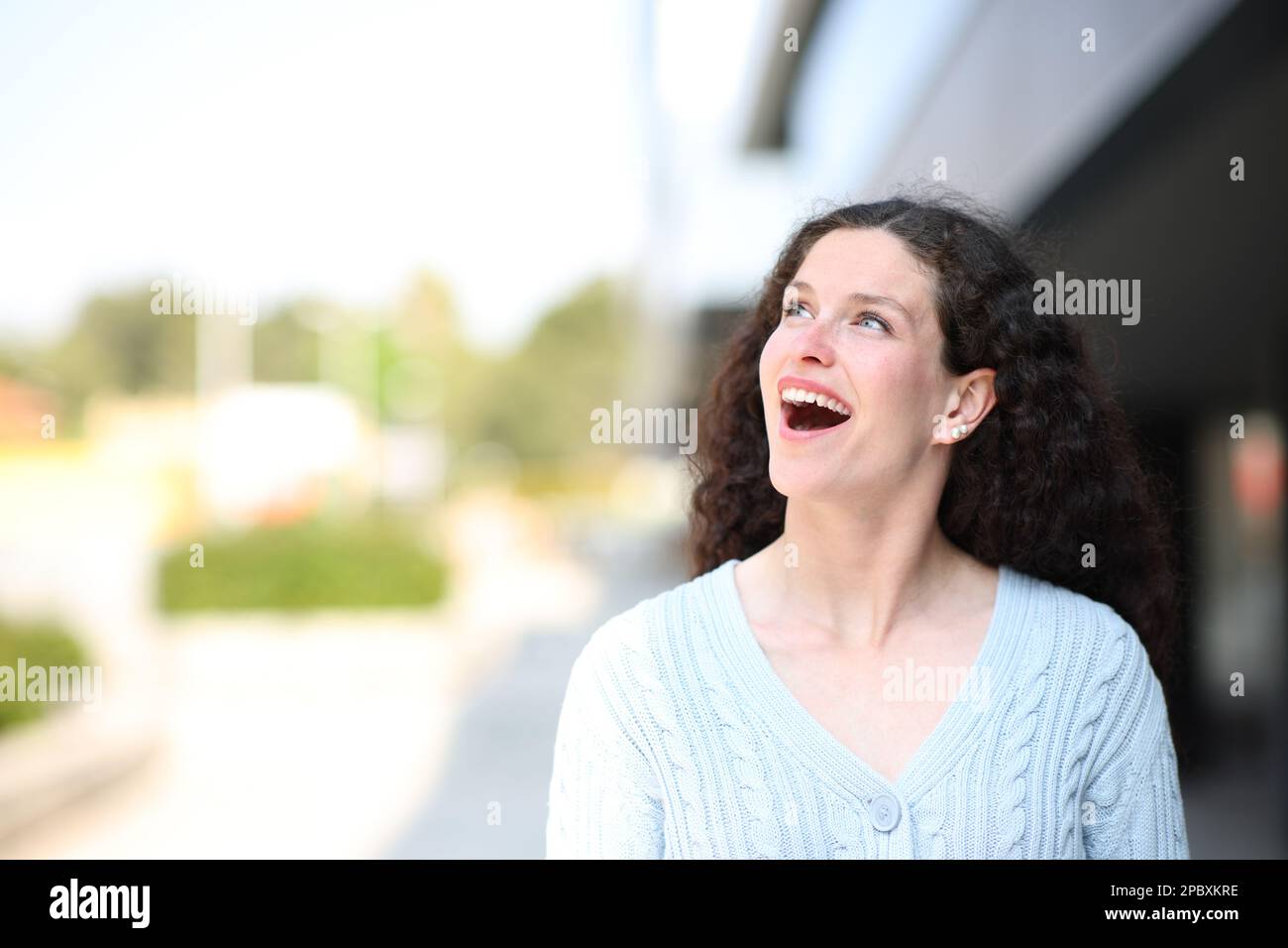 Vista frontale di una donna stupita in strada guardando di lato Foto Stock