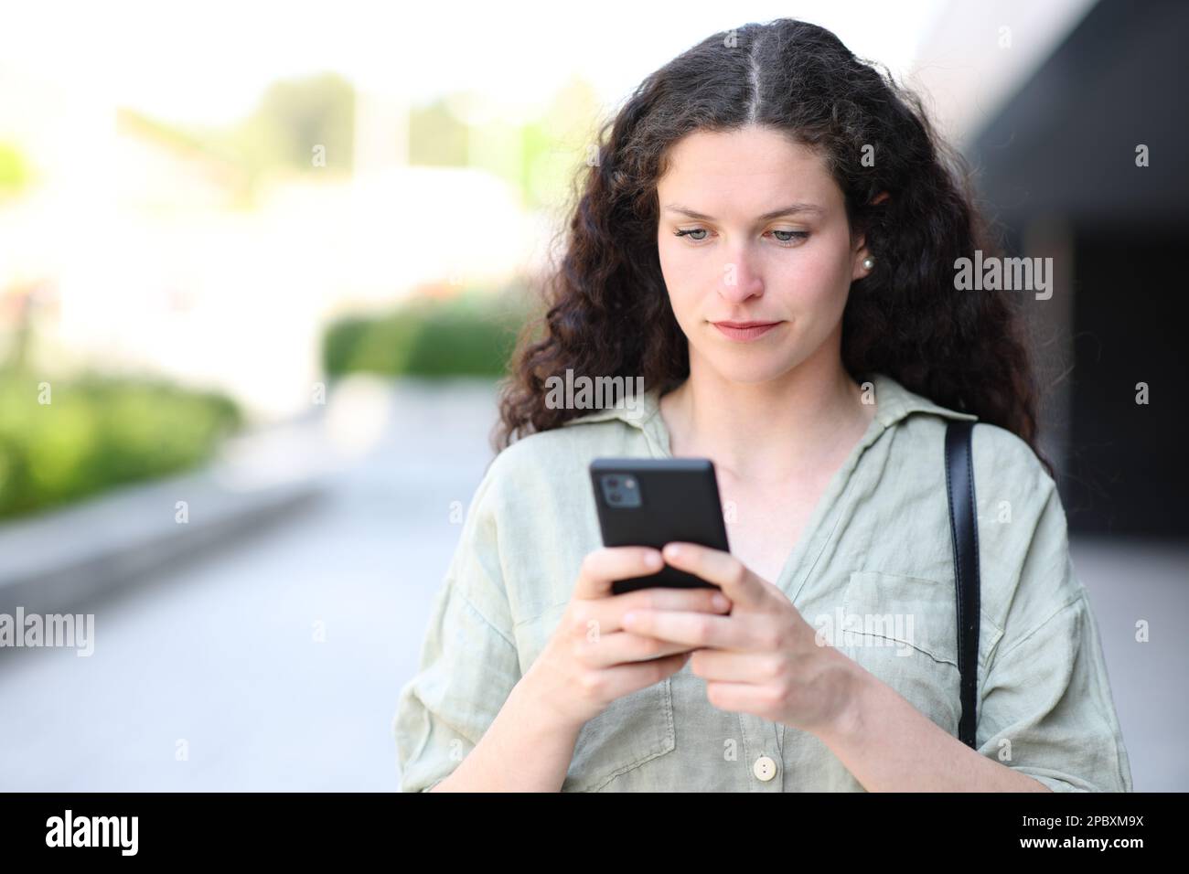 Ritratto di una donna che usa il telefono e cammina per strada Foto Stock