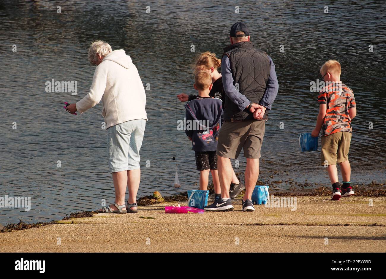 Due nonni si schiantano con i loro nipoti su una strada a Tobermory, Mull, Scozia. Regno Unito che mostra le loro linee di granchio e secchi colorati Foto Stock
